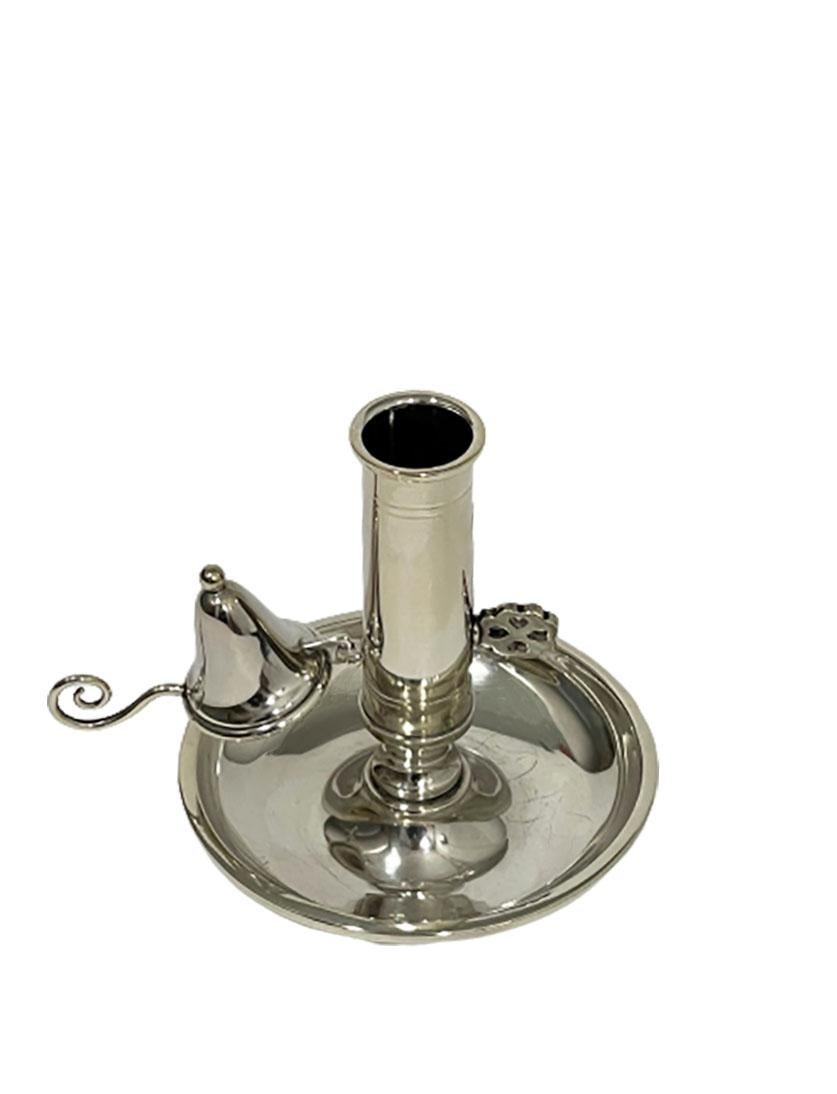 A small silver chamber candle stick with a separate candle extinguisher, which is hung with a hook. 
With slide in the stem to raise the candle. 
The rotary knob in the shape of a four-leaf clover has been opened to lock the slide. 
Shows some