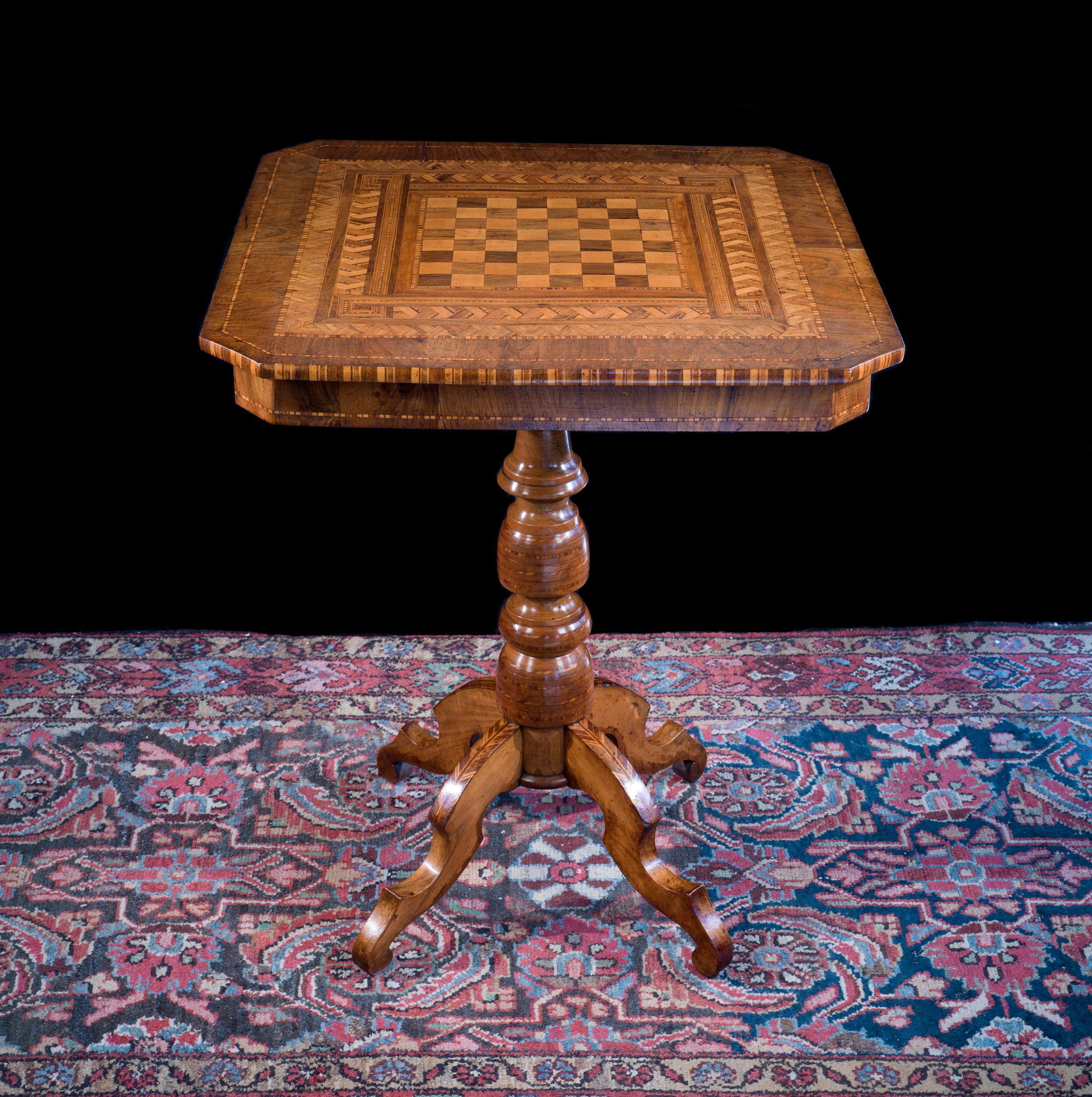 A small walnut Sorrento ware inlaid games table. The square top with canted corners and a central marquetry chess board surrounded with intricate geometric inlay is raised on a turned column supported on four shaped splayed legs.

Italian, circa