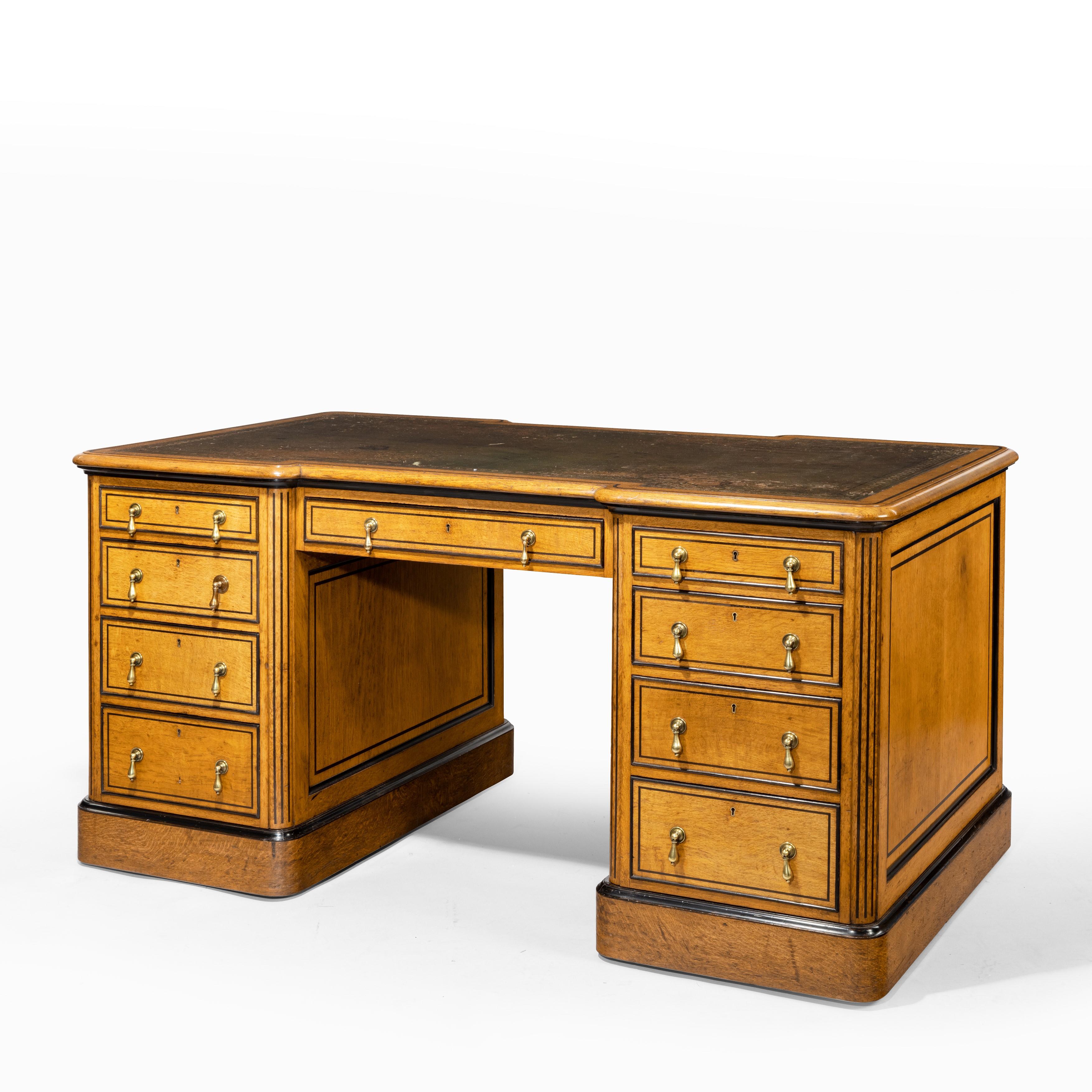 A small Victorian oak and ebony partner’s desk, attributed to Holland and Son, the shaped rectangular leather-inset top set above a knee-hole with a central drawer flanked, on one side, by four cedar lined drawers in each pedestal and on the other