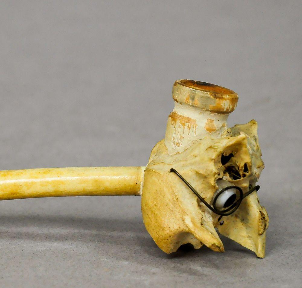 A small antique pipe made of chicken bones. The bowl is made in the shape of a face with glass eyes. Executed in Germany, circa 1900.

Measure: Length 5.91