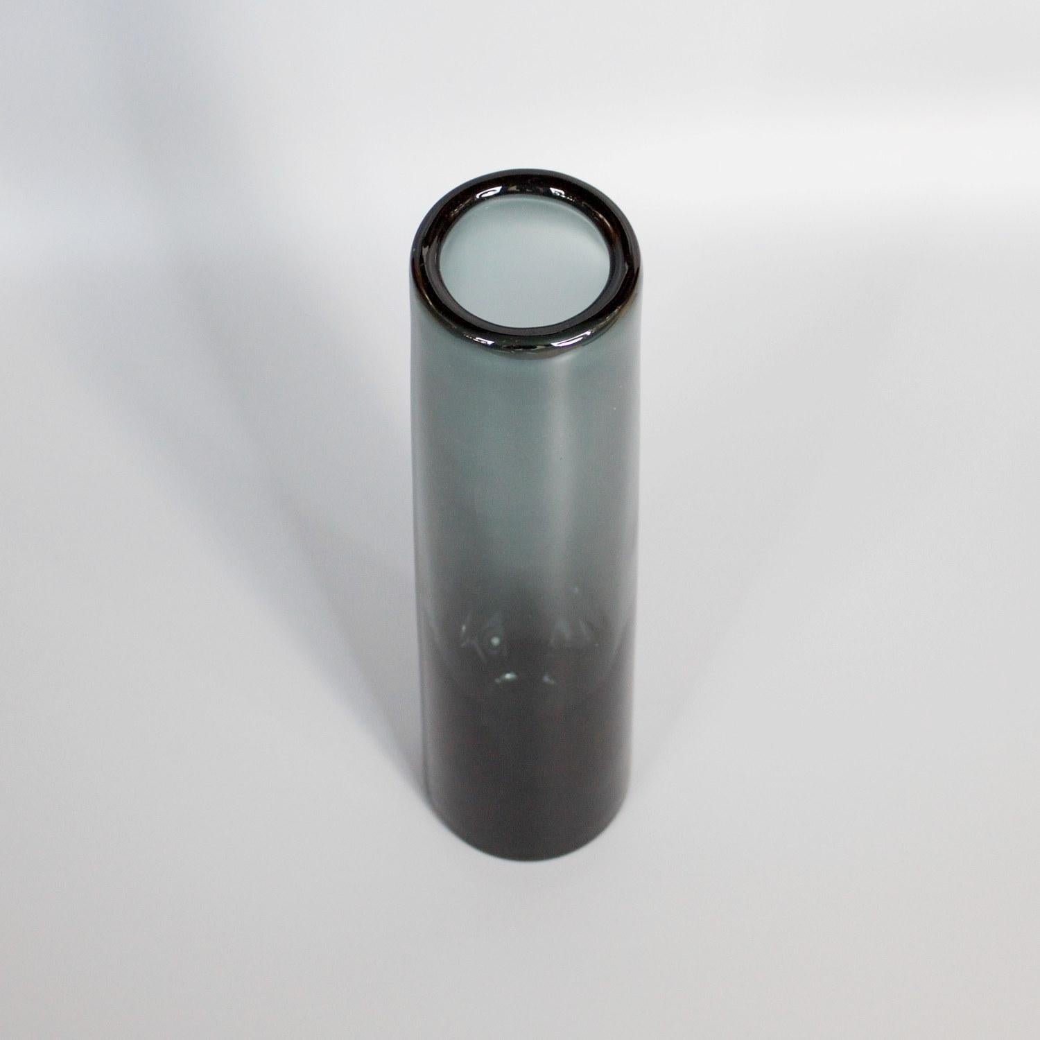 A smoked grey cylinder vase by Danish glassmaker Per Lütken for Holmegaard Glassworks. Signed and Dated 1962

Dimensions: H 30cm D 6cm

Designer: Per Lütken (1916-1998)

Origin: Denmark

Date: 1962. 

Holmegaard Glassworks is located in