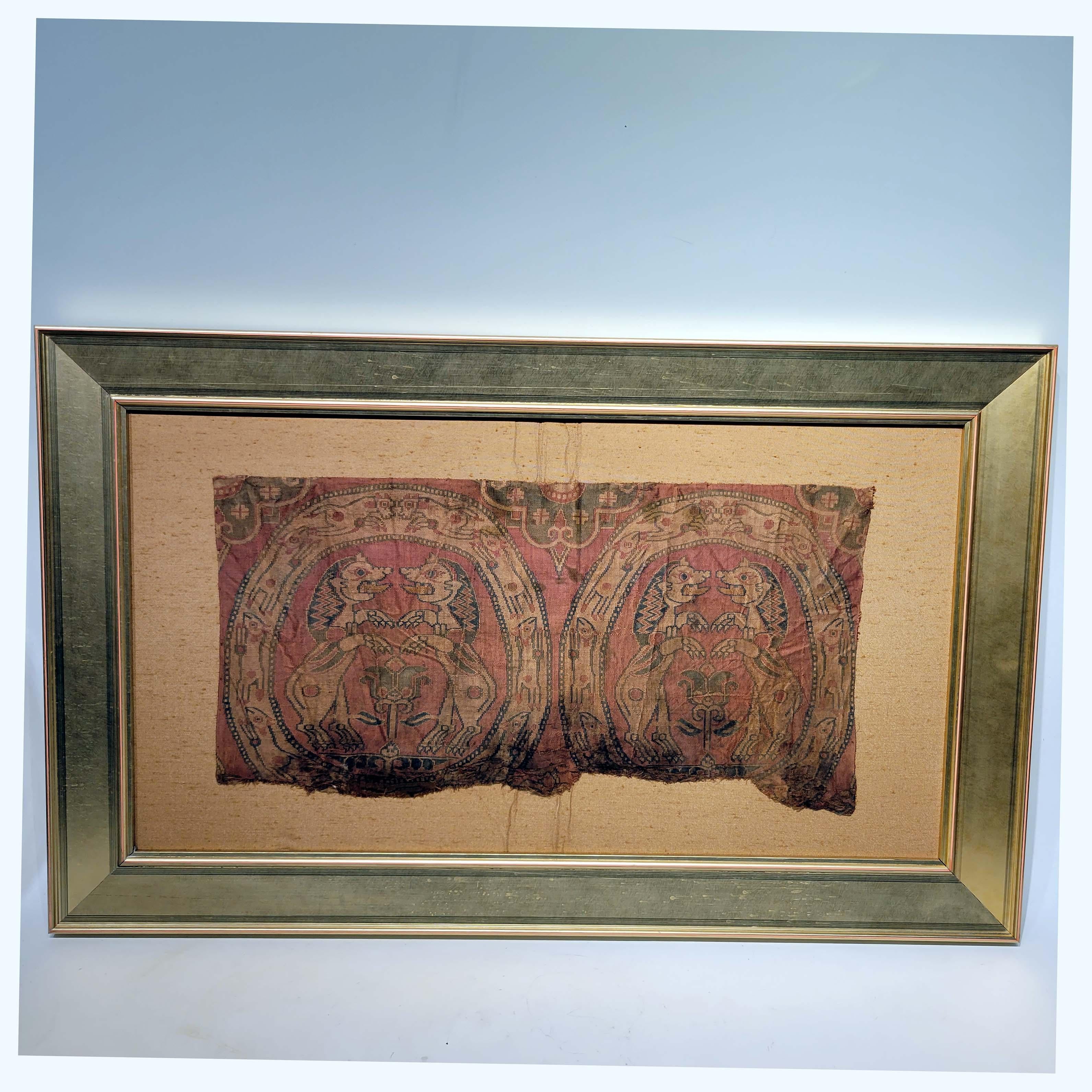 A Sogdian silk samite fragment with confronting lions
Central Asia, 7th-9th century
of irregular rectangular form, woven in red, blue and cream silks, depicting two large roundels enclosing two confronting lions standing on split palmettes with a