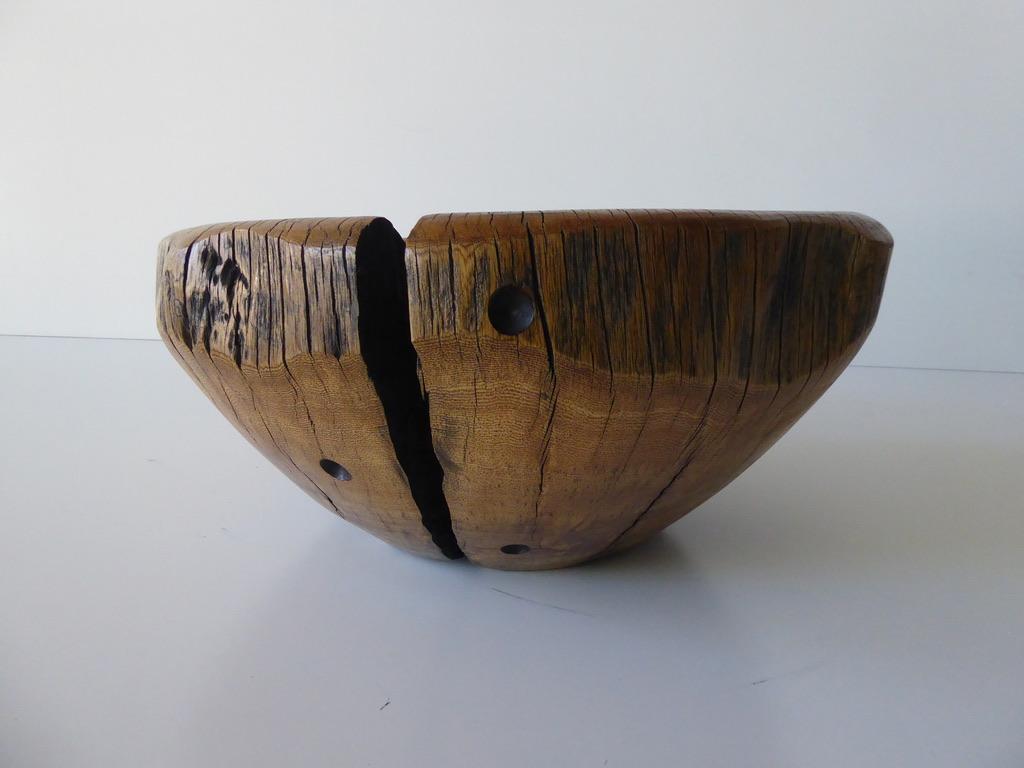 A solid ficus wood bowl by contemporary American artist Daniel Pollock. Dan hand-selected this sculptural piece of reclaimed ficus that has been carved and dried, creating natural organic fissures. The fissure that runs down one side is held