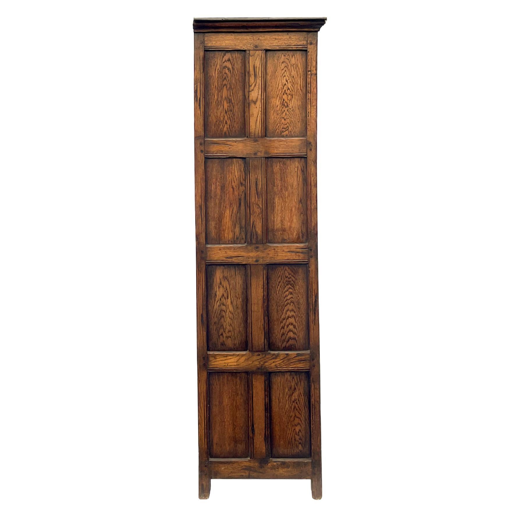 A solid Oak Jacobean-Style wardrobe, the doors with relief carved linenfold panels and raised panel sides, with hand forged iron hardware, pegged construction, English, circa 1900.