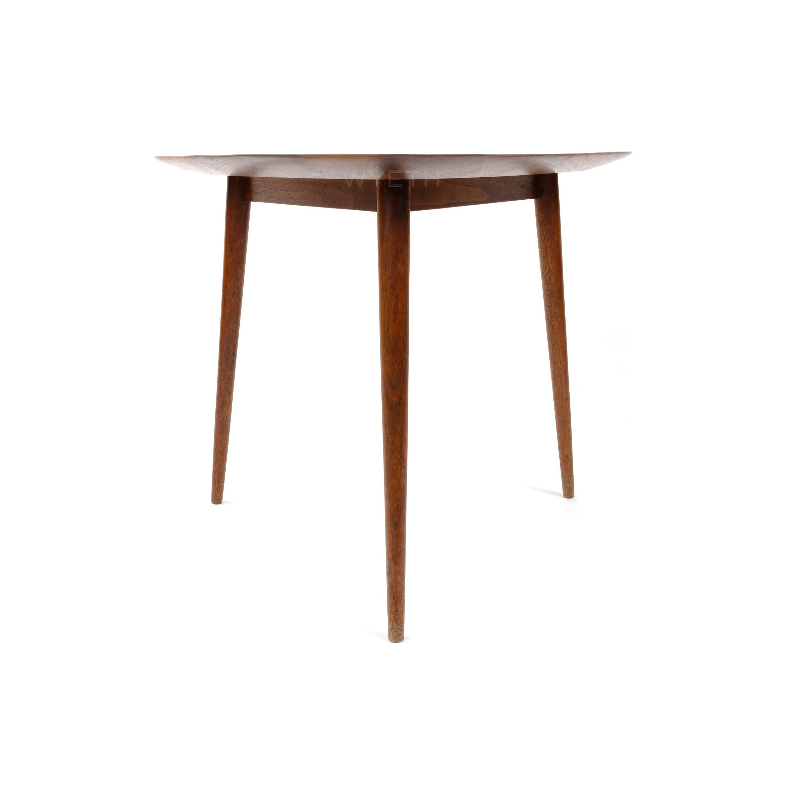 A simple handcrafted side/end table with a top of richly grained walnut and three splayed dowel legs joined to the top with through tenons.