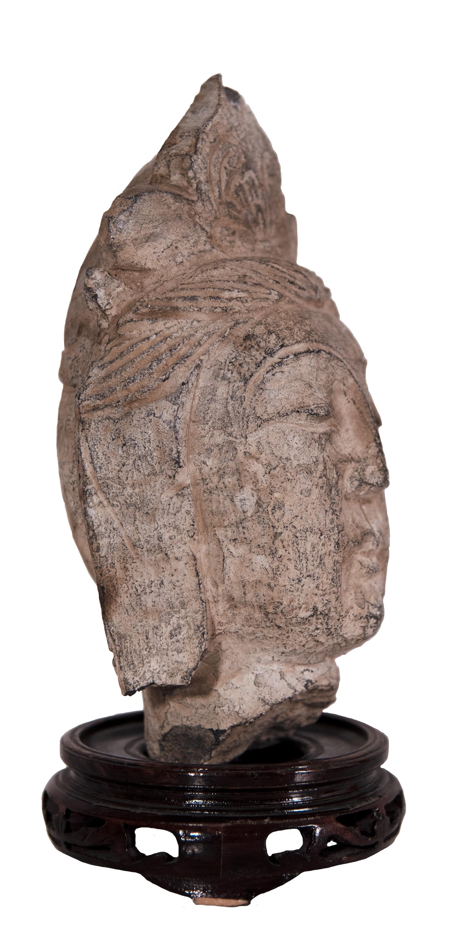 A South-East Asian stone bodhisattva head with a wood stand.

Circa 1930-40.