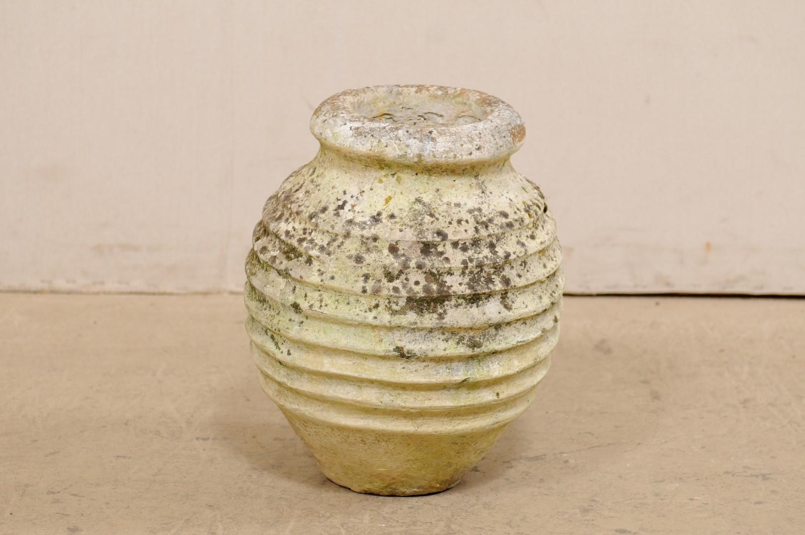 A Spanish cast-stone pot from the 19th century. This antique vessel from Spain is bulb-shaped and has a thick and pronounced lip at top, a nicely ribbed texture around it's body, and rests upon a flattened base. The jar stands approximately 15.75