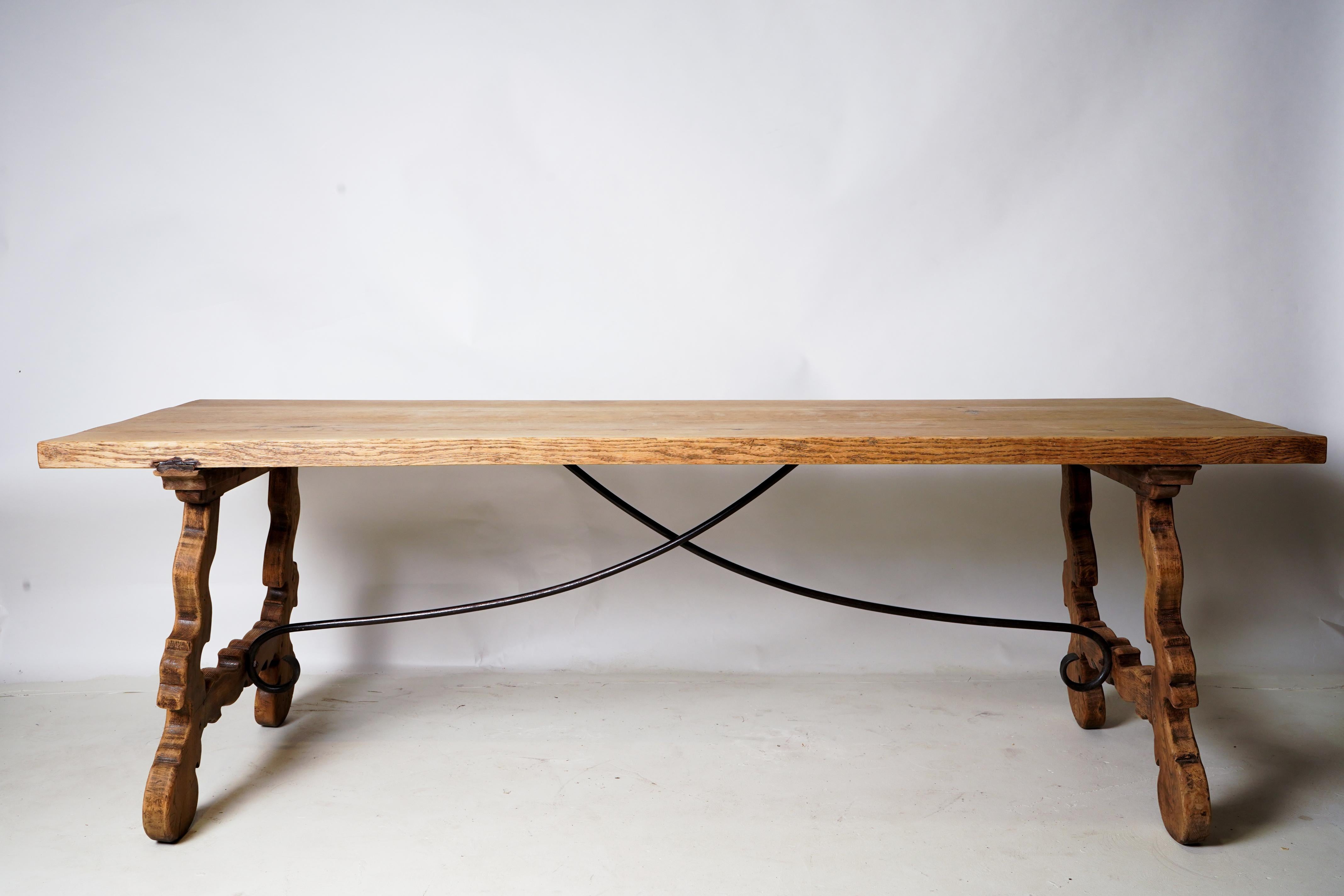 This extremely sturdy Oak table is made in the Spanish Baroque style, with elaborately carved legs and had-forged iron braces running from the center of the table top to each leg. The 2