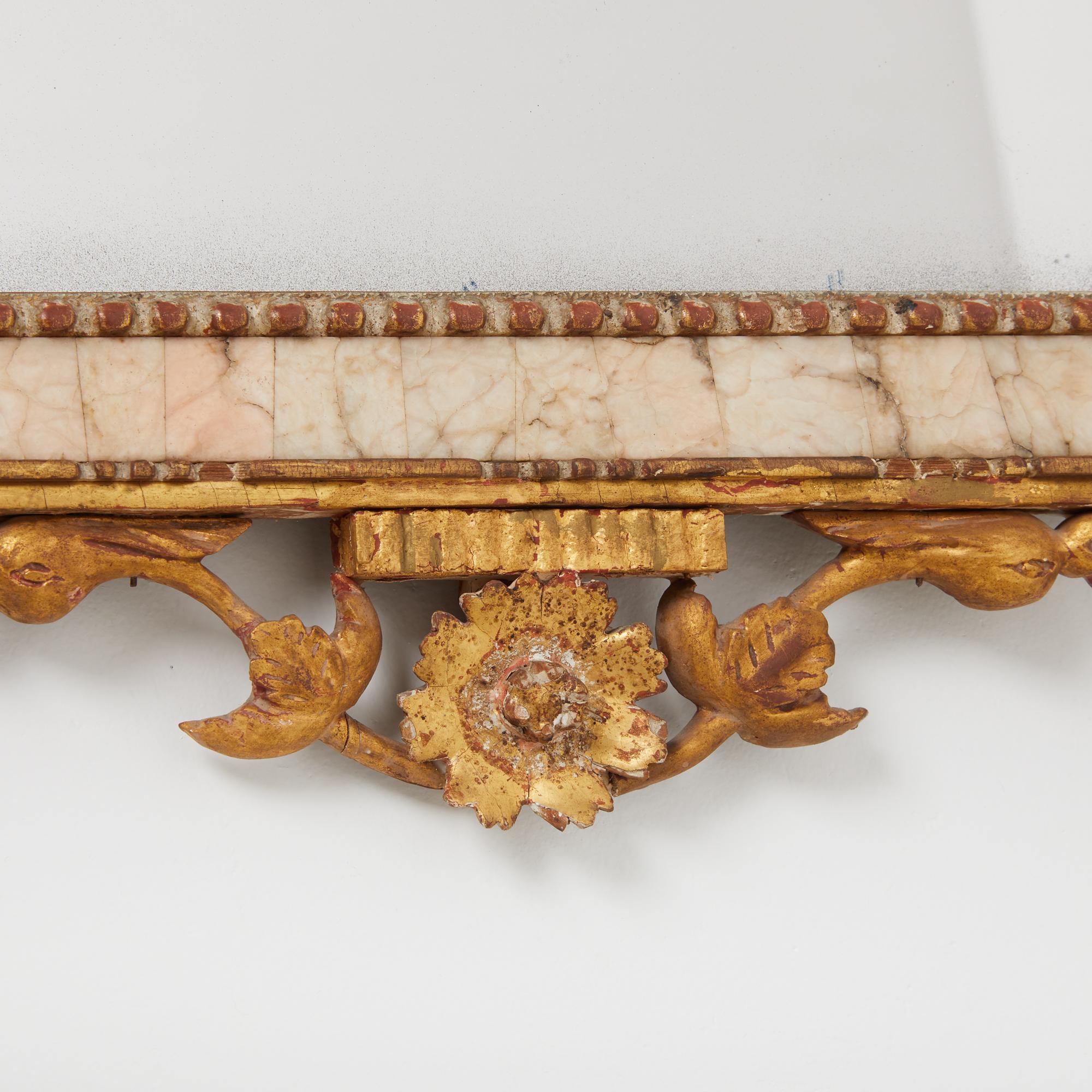 An early 19th century Spanish Louis XVI Style Bilbao mirror with pale pink marble veneer columns and gilt wood and gesso flowers, urn motifs, and granulated texture on frame. Circa 1820.

Measures: 27” height x 19” width x 2” depth

Mirror