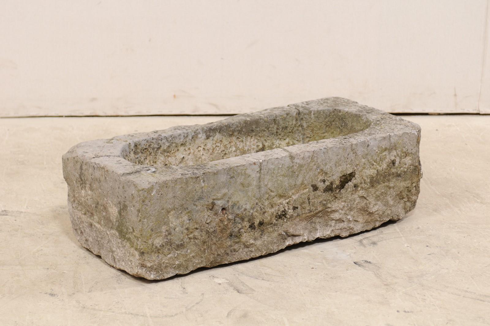 A Spanish carved stone basin or planter from the 19th century. This antique trough from Spain, has a rectangular shape exterior with elongated oval basin interior, and has been hand carved out of a single piece of stone. The basin has a nicely