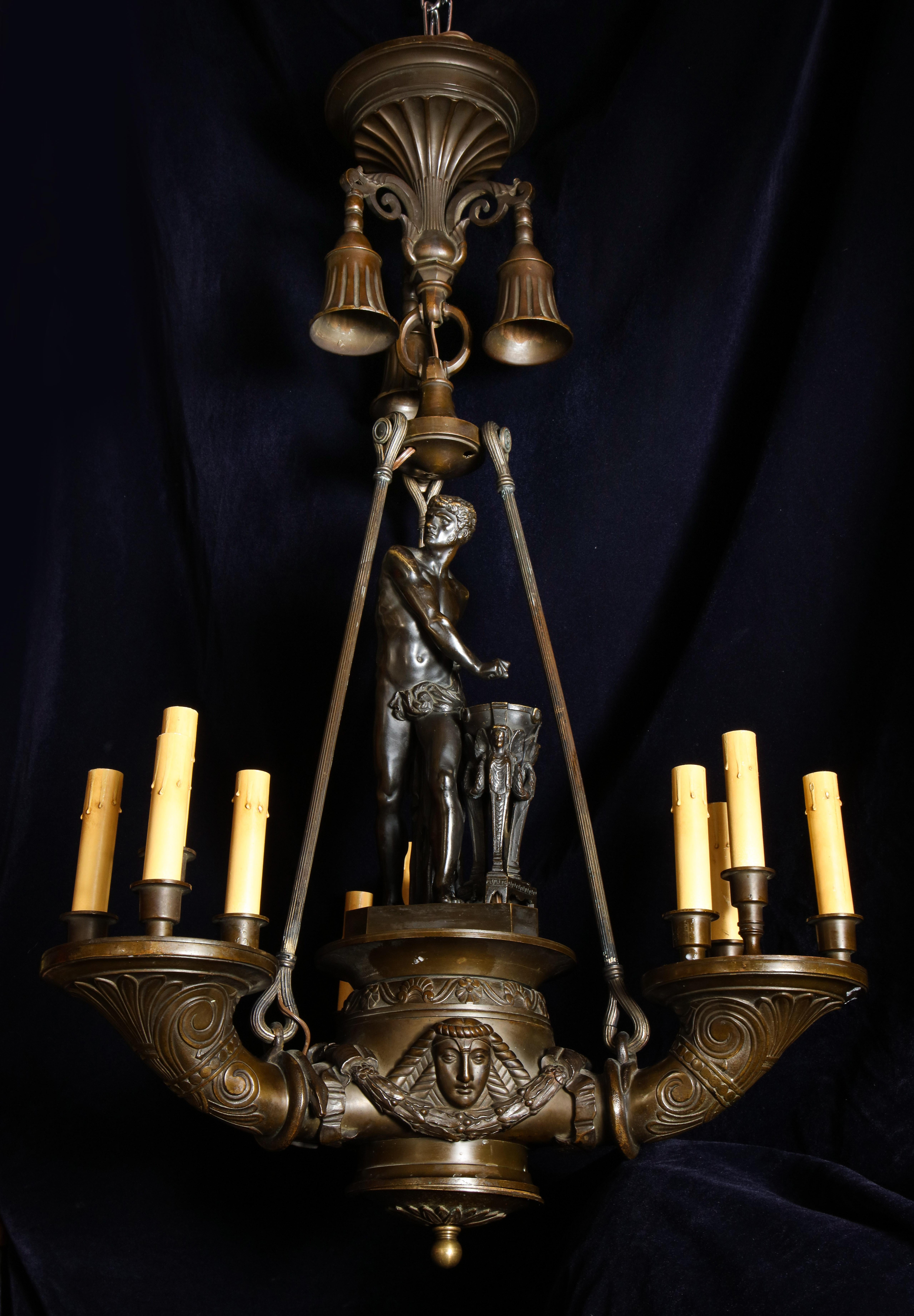 Un spectaculaire et grand lustre figuré italien néoclassique ancien en bronze patiné à plusieurs lumières avec de superbes détails embellis par la figure centrale d'un homme néoclassique et orné de masques figurés néoclassiques.