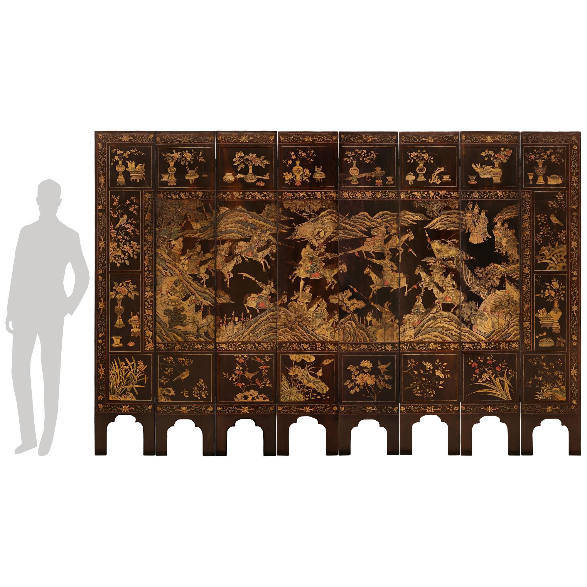 A spectacular and most impressive Chinese 18th century Coromandel Lacquered screen. Each of the eight panels are raised by two feet formed from an urn shaped arch below a foliate decorated band. The center of each panel joins together to depict