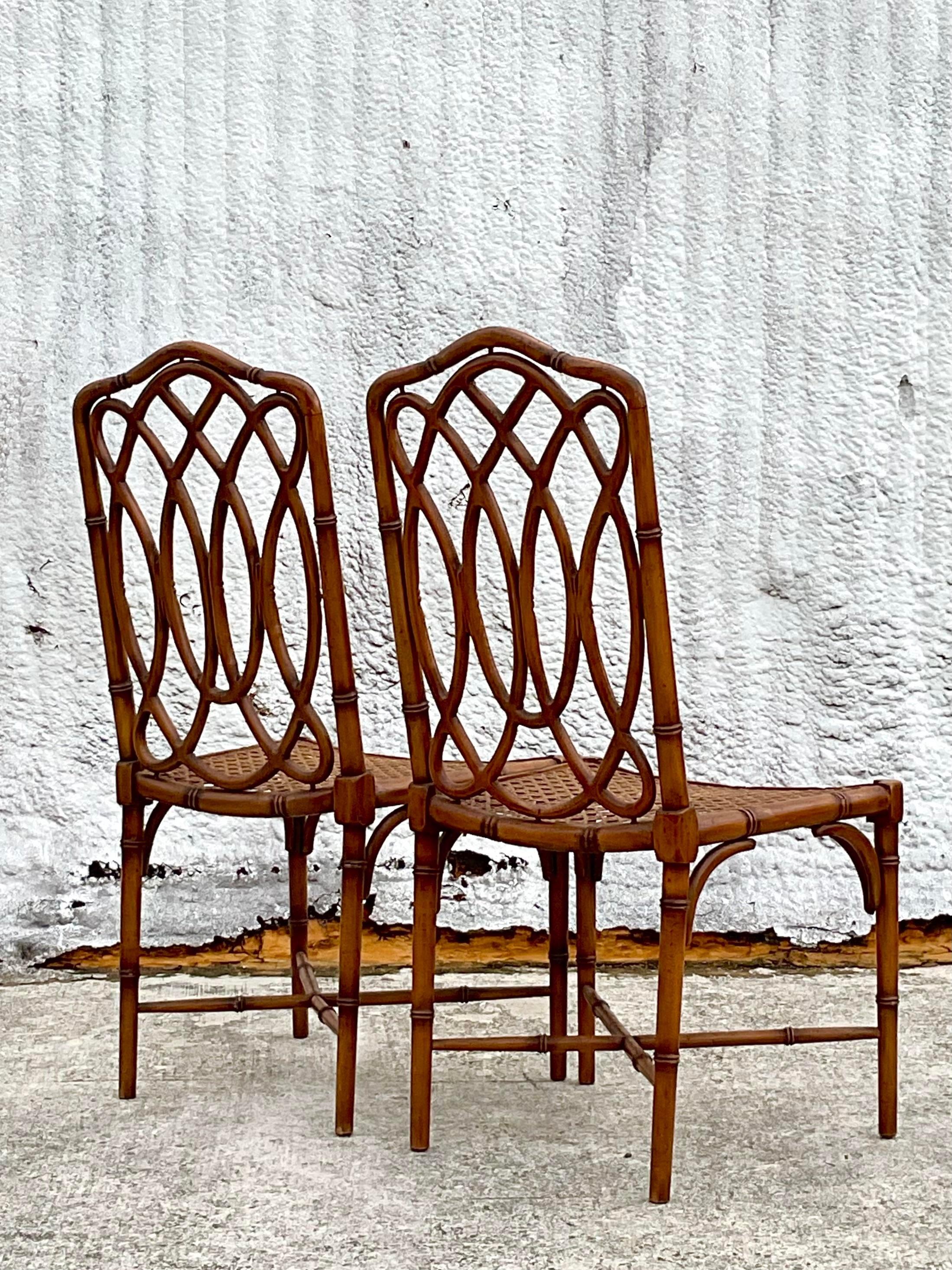 A spectacular pair of vintage Coastal dining chairs. Beautiful carved bamboo frame with inset cane seats. Marked made in Italy on the bottom. Acquired from a Palm Beach estate.
