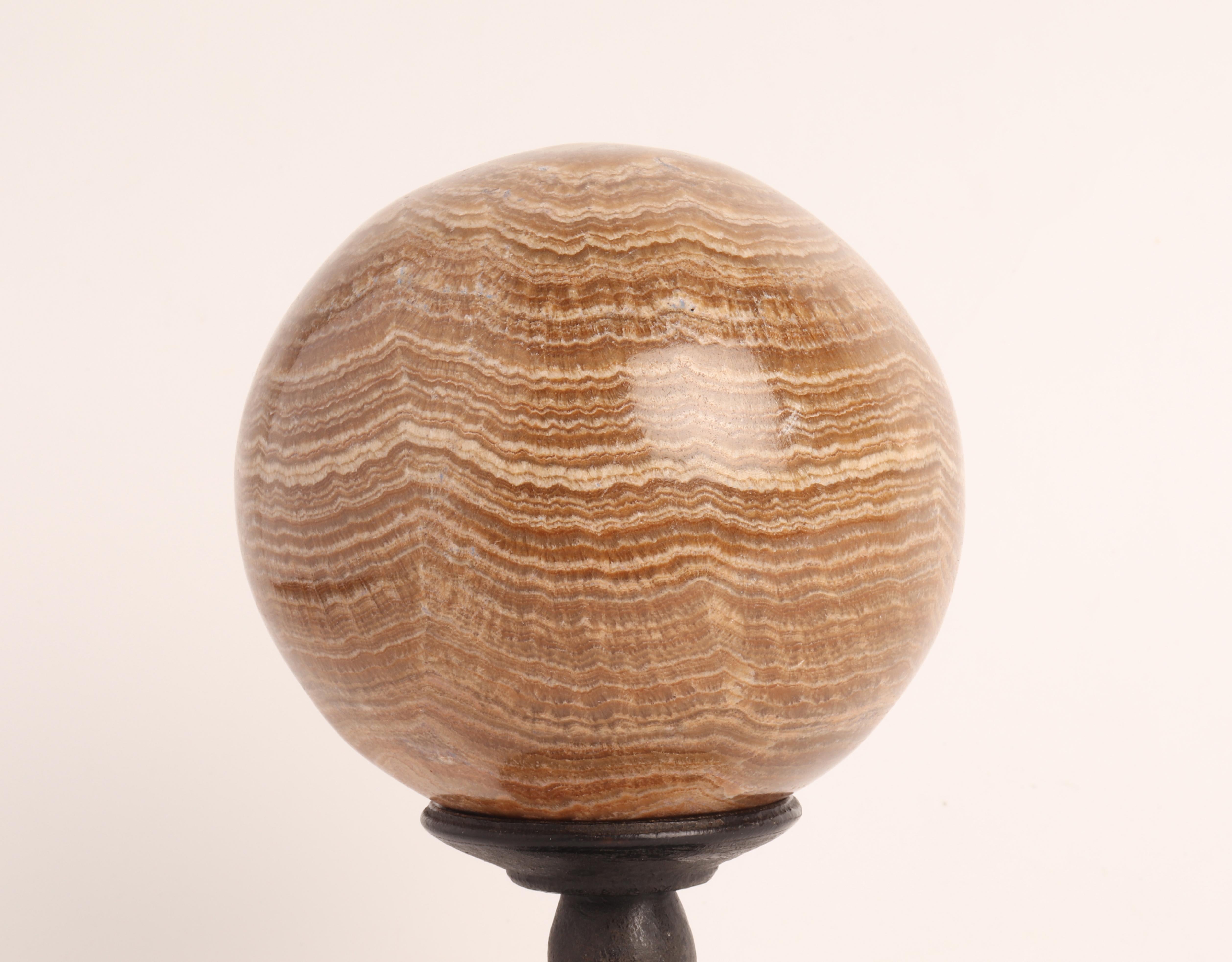 A sphere of Aragonite stone, resting on a base, made out of ebonized wood that has a column with a wavy profile that opens upwards with a concave top. Italy circa 1870.