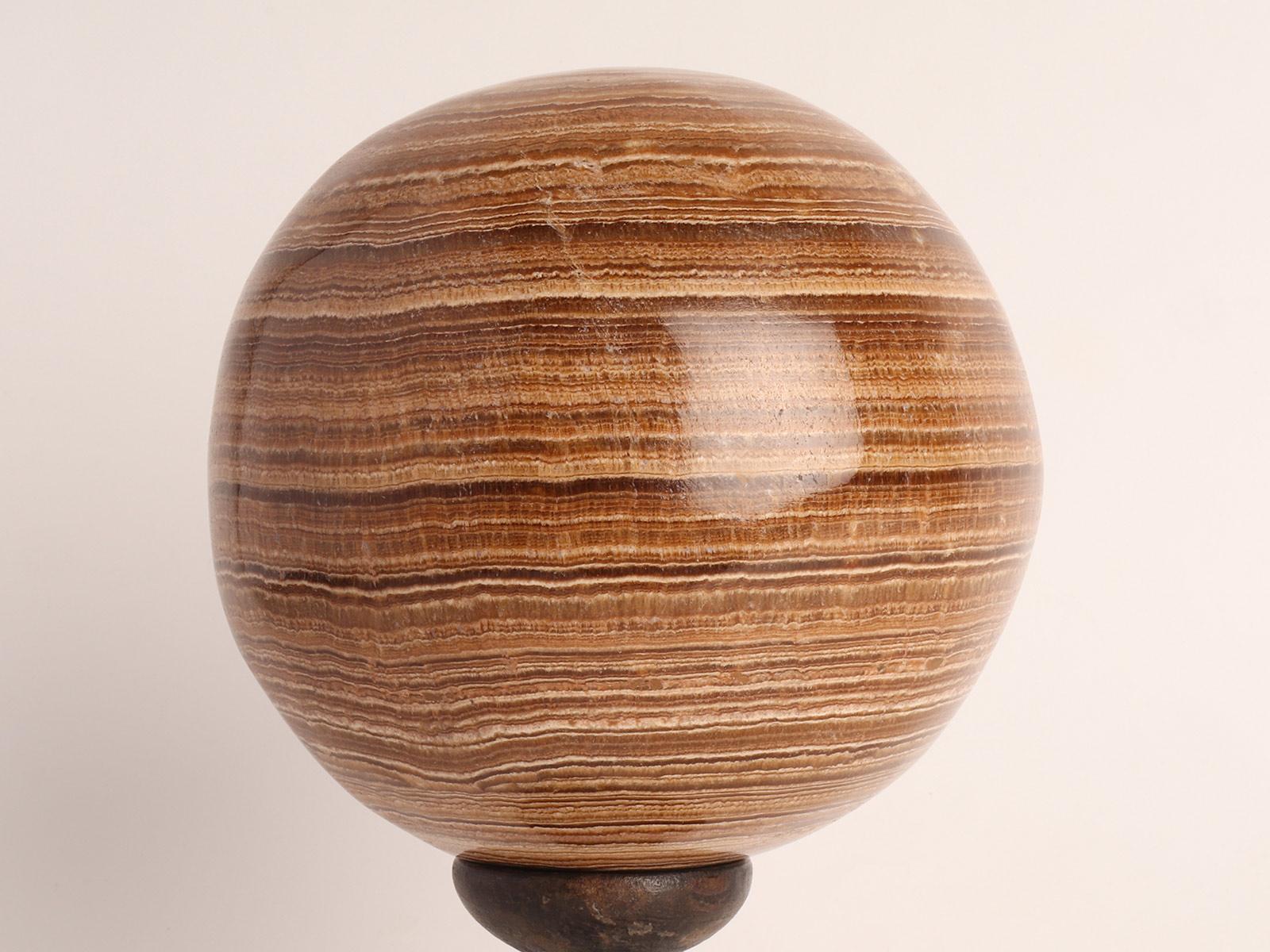 A wunderkammer Grand Tour's souvenir. A sphere of Aragonite stone, resting on a base, made out of ebonized wood that has a column with a wavy profile that opens upwards with a concave top. Italy circa 1870.