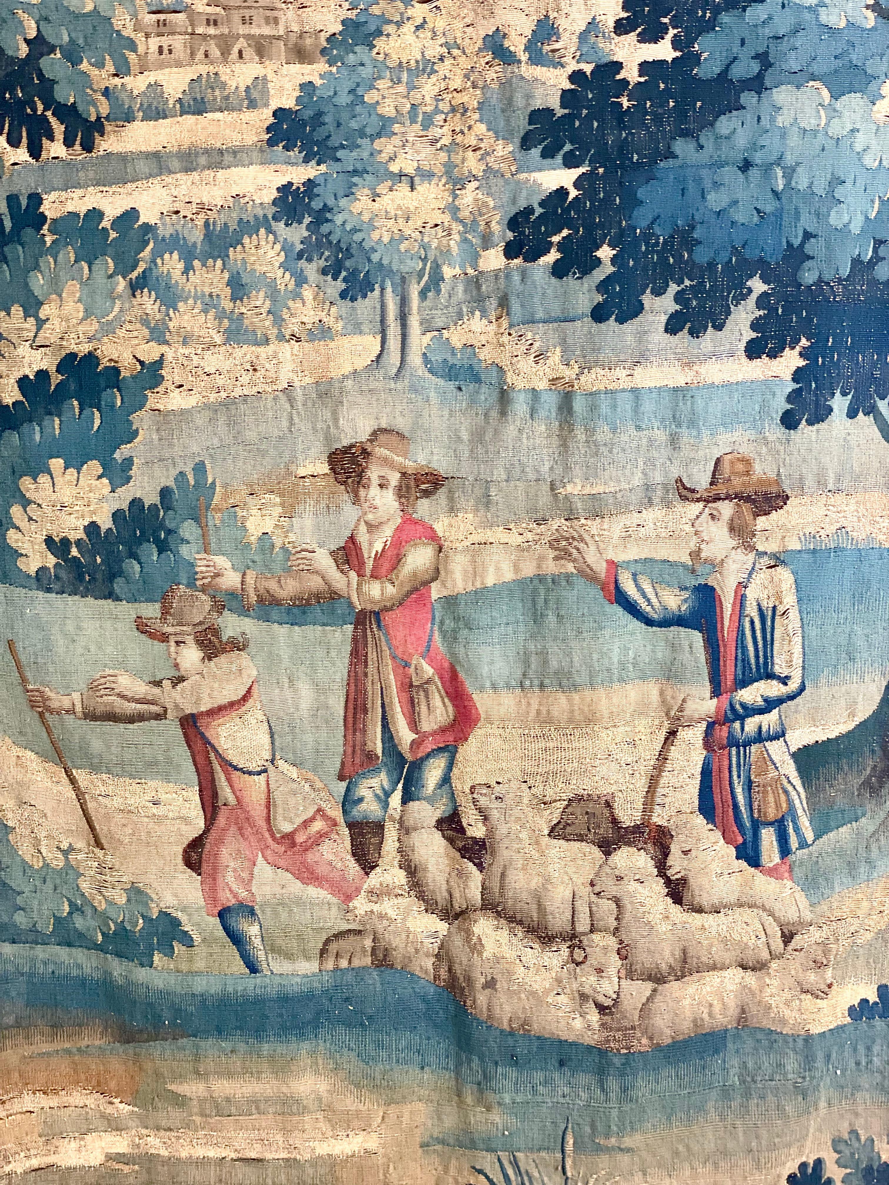 A luxurious 18th century Aubusson tapestry, depicting a rural landscape in which three shepherds watch helplessly as one of their lambs is carried off by an opportunistic wolf. Hand-woven in wool, in predominantly green and cream hues with a border