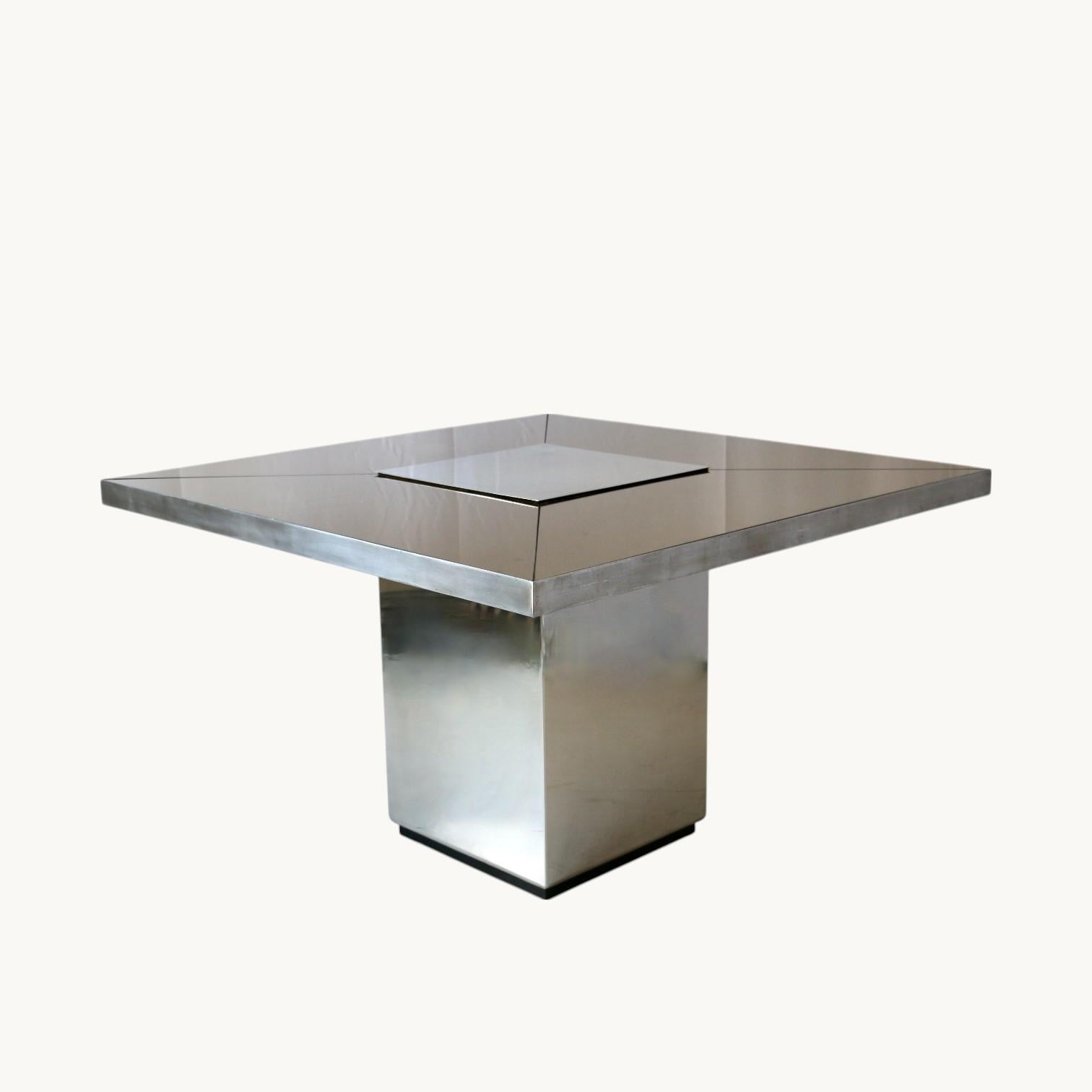 Tavolo quadrato con gamba centrale rivestita in acciaio inox e piano in vetro fumé in quattro parti, la parte centrale e la fascia superiore in acciaio inox spazzolato. Italia anni '70.
