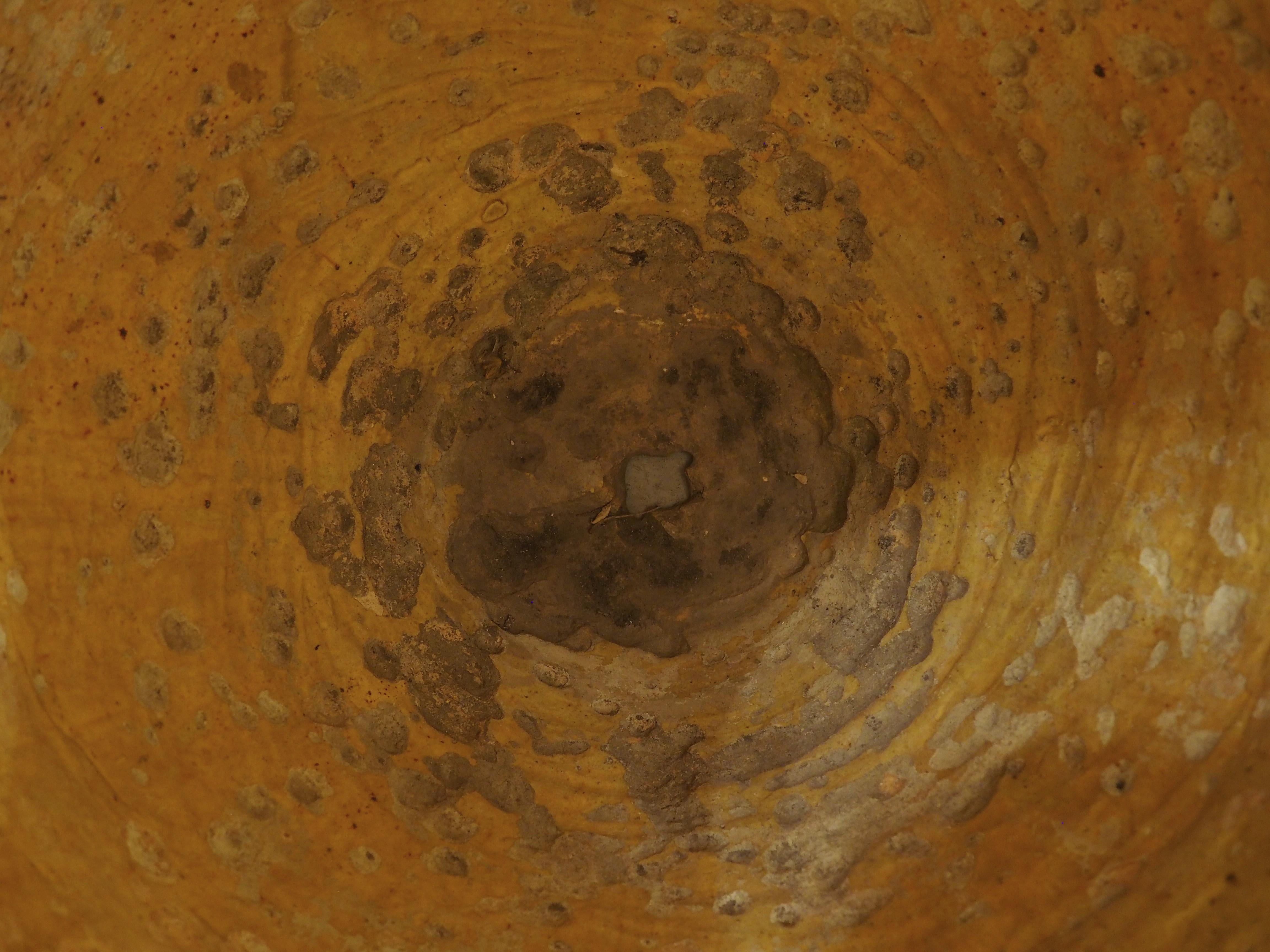 Plus d'informations bientôt...

Appelé pot Biot (du nom de la ville française d'où il est originaire au Moyen Âge), ce pot bulbeux en terre cuite a une teinte beige avec un anneau de glaçure jaune près de l'ouverture.  La glaçure est estampillée