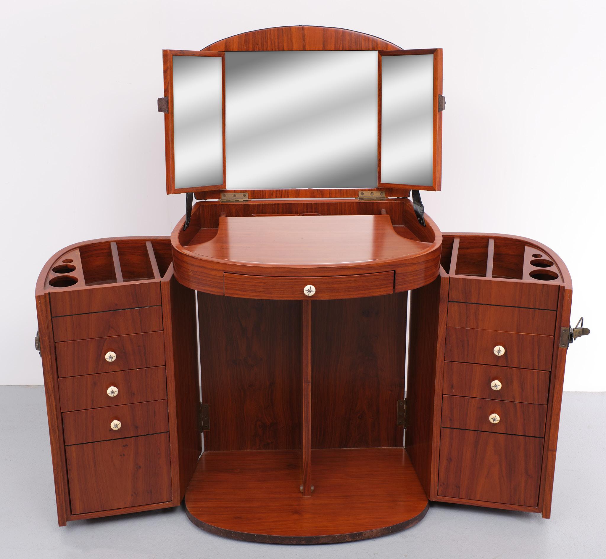 A 'Starbay Marie Galante' rosewood finish bow front dressing table, the lift up top revealing a triptych mirror over a pair of cupboard doors and two banks of drawers within, with bone inset logo, Chic elegant and practical, the portable