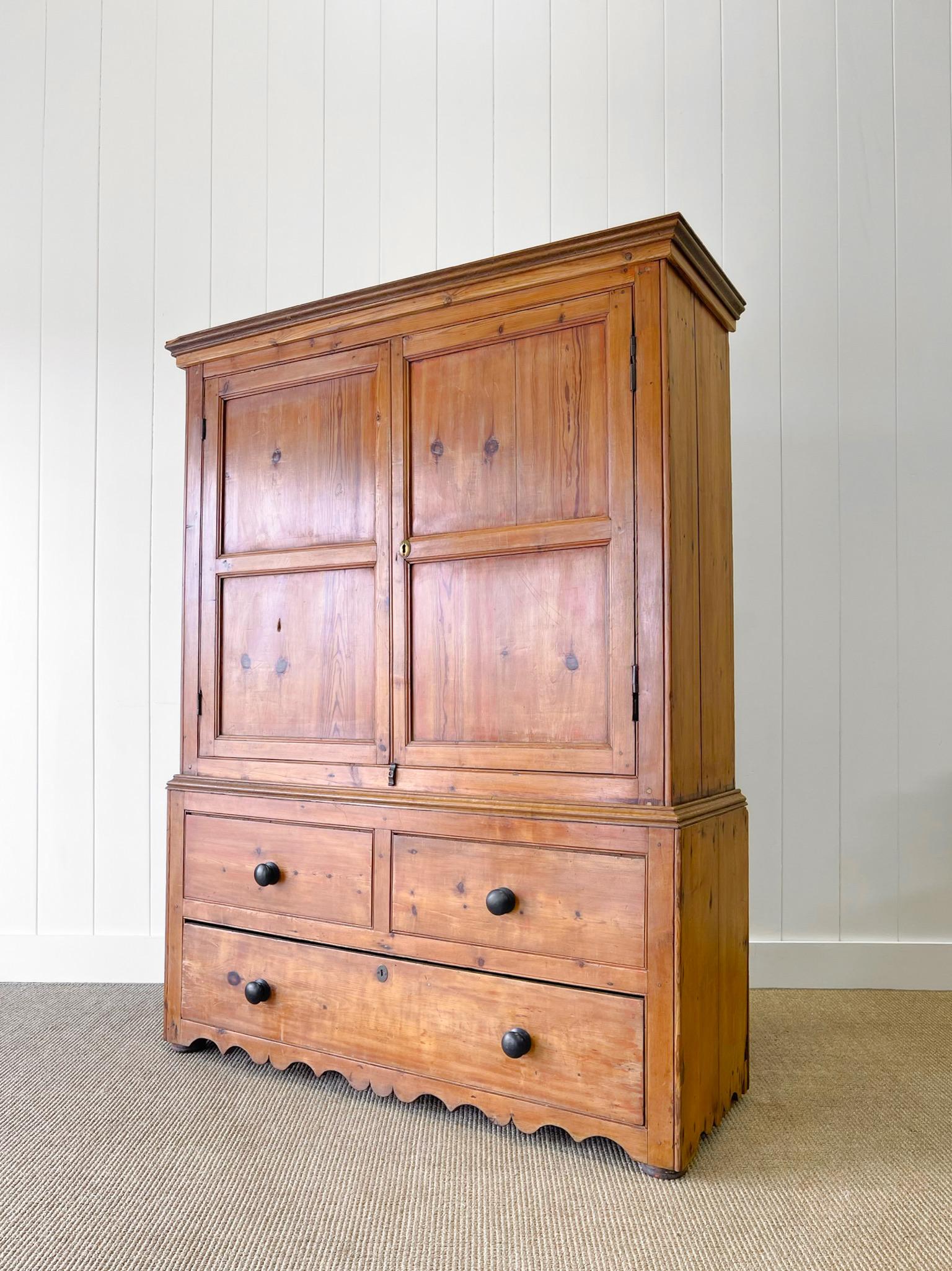 A charming English 19th century cupboard. Decorative paneled doors. The two drawers on the top of the base do NOT open. They are dummy drawers. The bottom single drawer opens as usual. All sits atop bracket feet with a subtly scrolled apron.
