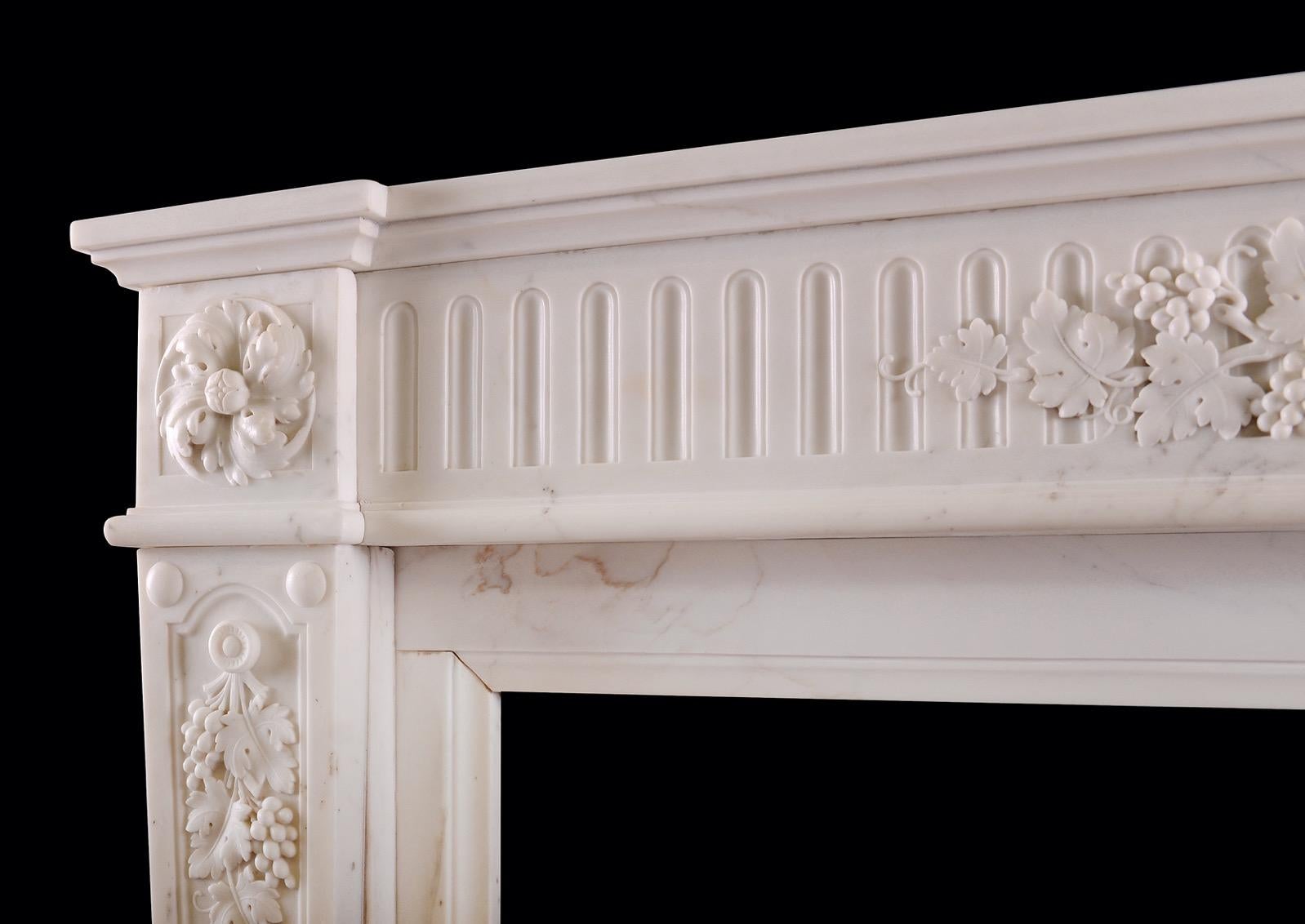 A fine quality Statuary marble fireplace in the Louis XVI style. The tapering, stop-fluted jambs surmounted by panel carved with grapes and leaf work with swirling rosette paterae above. The fluted frieze with carved grapes and leaf work throughout.
