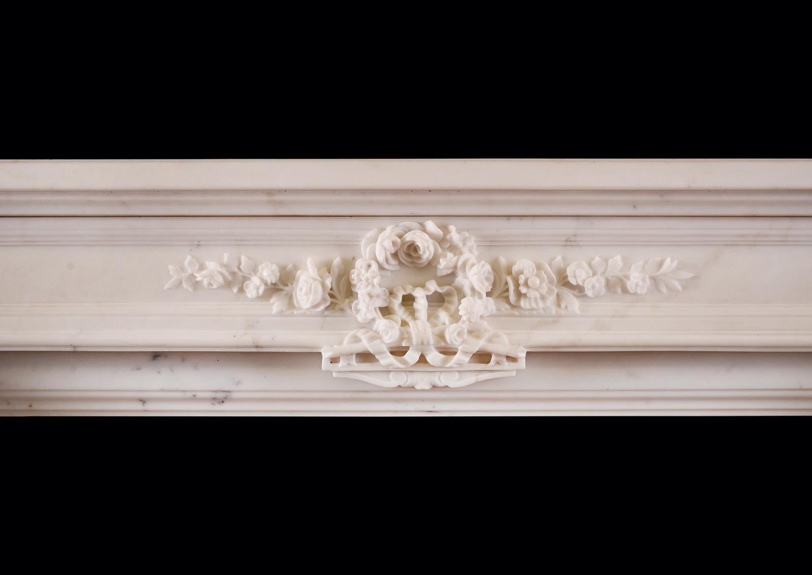 Cheminée statuaire française en marbre blanc du XIXe siècle de style Louis XVI. Les cannelures avec des cosses sculptées, surmontées de panneaux sculptés de rubans et de feuillages. La frise lambrissée avec des fleurs et des feuillages sculptés au