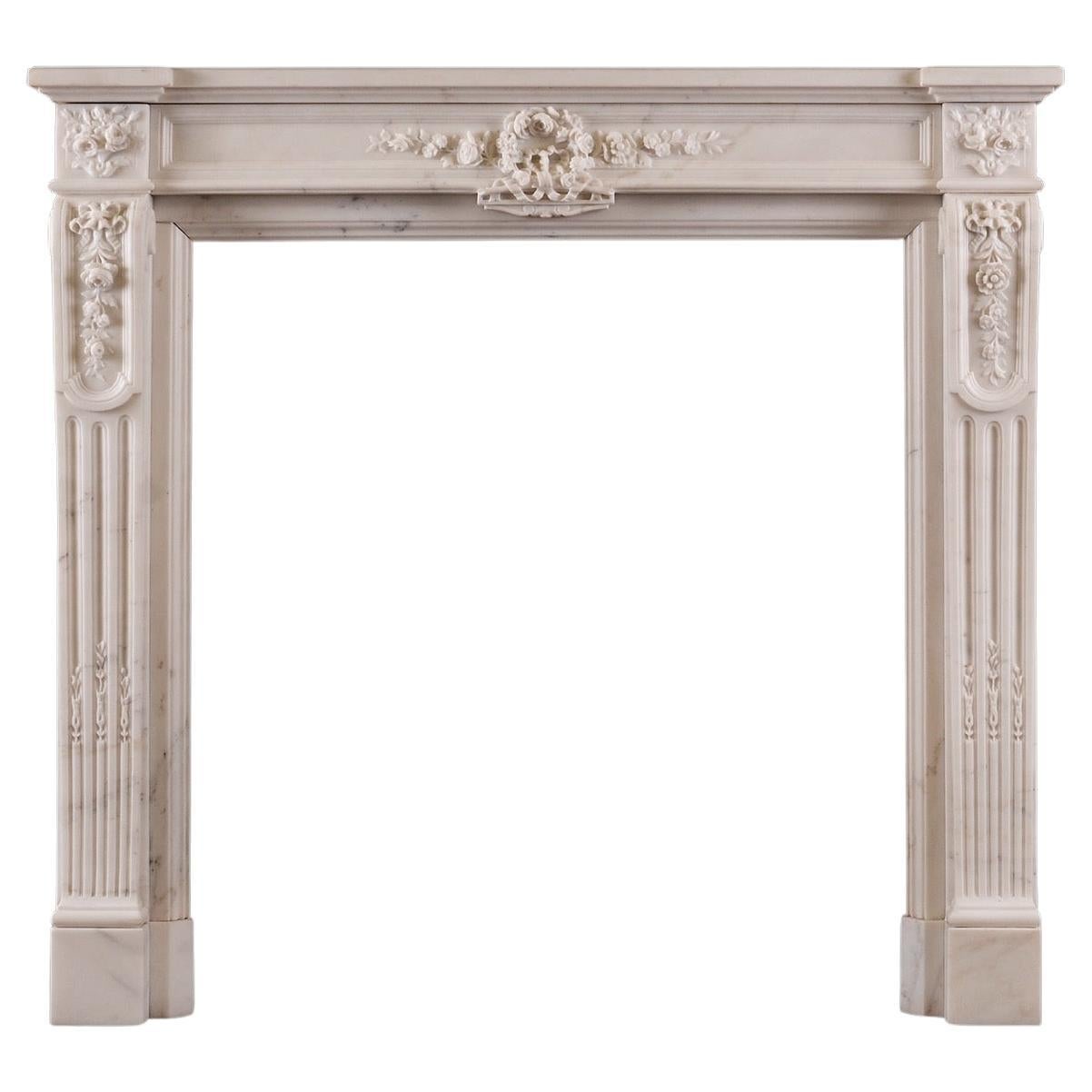 Une cheminée statuaire en marbre blanc de style Louis XVI.