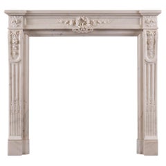 Une cheminée statuaire en marbre blanc de style Louis XVI.