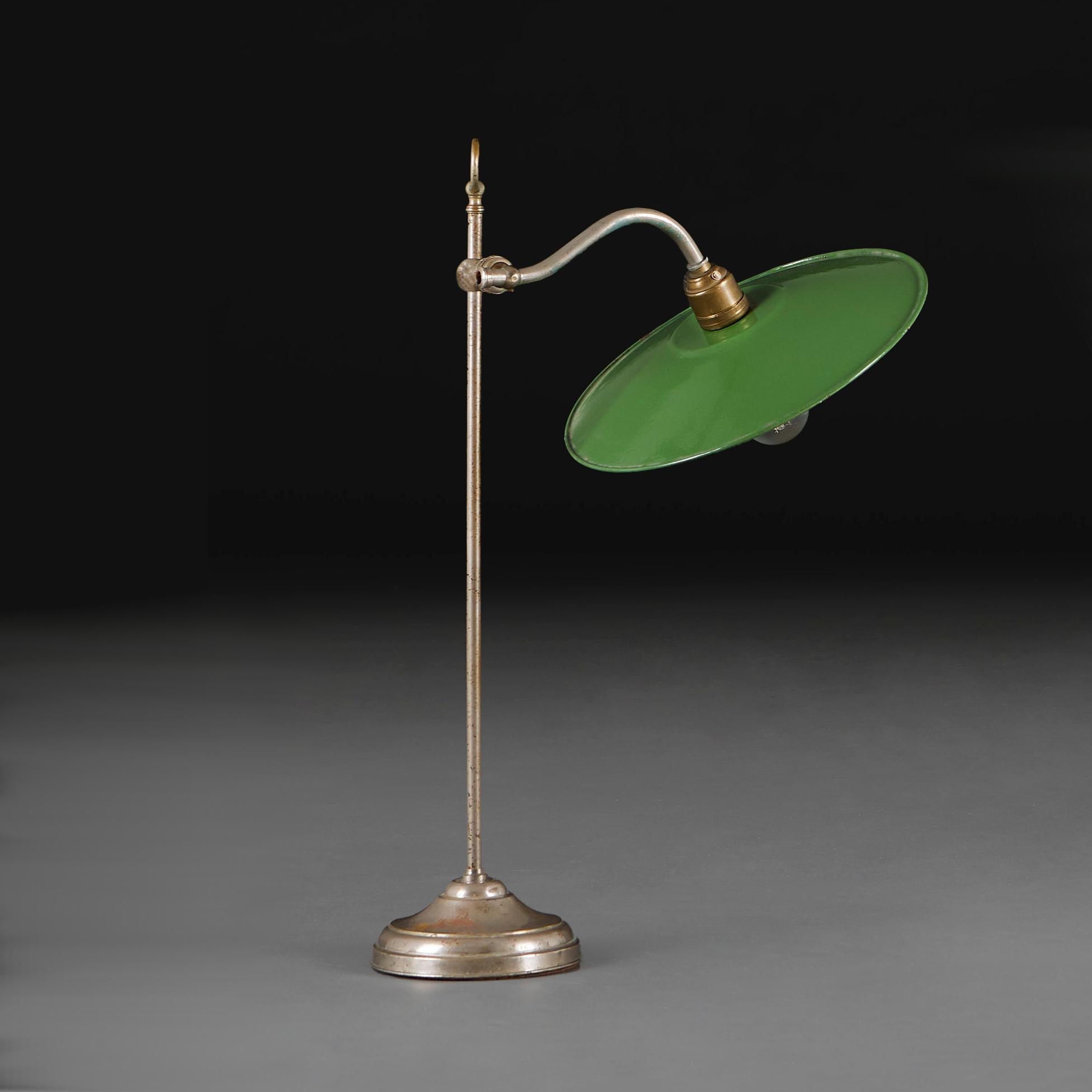 England, um 1920

Eine englische Industrie-Schreibtischlampe aus dem frühen zwanzigsten Jahrhundert, mit verstellbarem Arm und Ständer aus poliertem Stahl auf einem runden Sockel, mit flaschengrünem Emaille-Schirm in Form einer Scheibe mit weißer