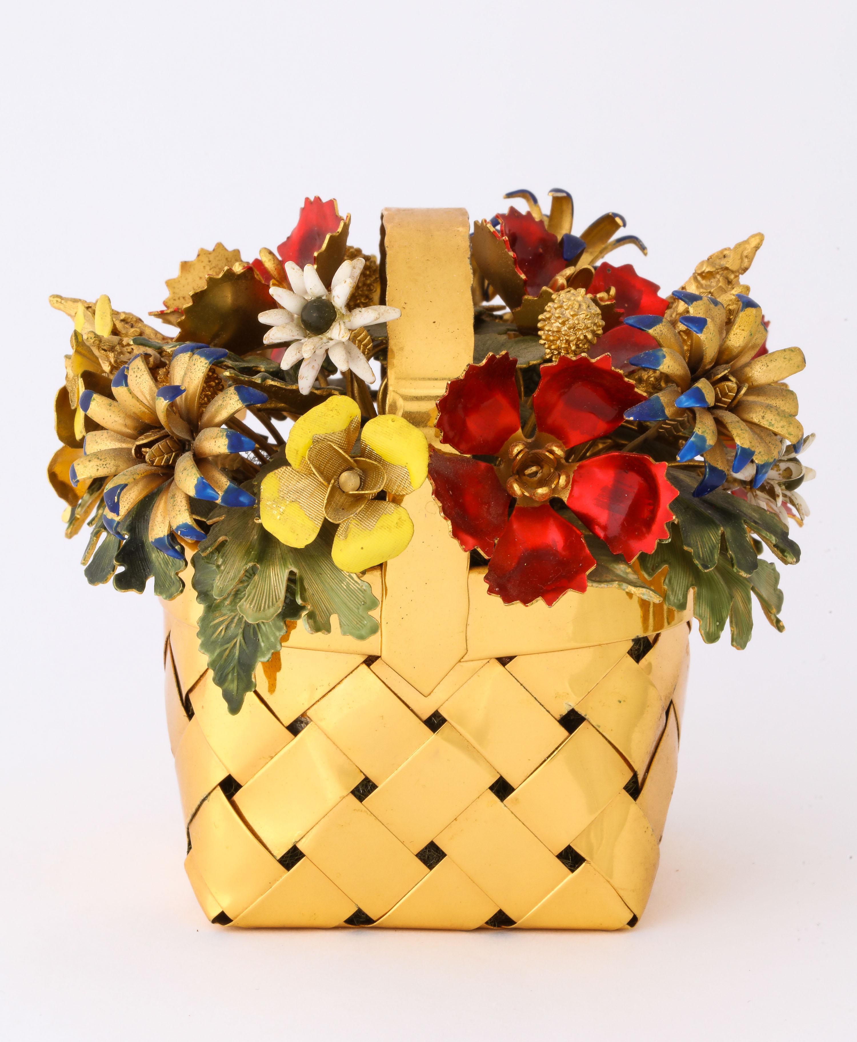 A silver gilt and enamel table ornament basket by Cartier, circa 1950.

Designed by Jane Hutcheson for Cartier.

Modelled as a basket of flowers, the woven silver-gilt punnet filled with a spray of various enamelled flowers, buds and leaves.