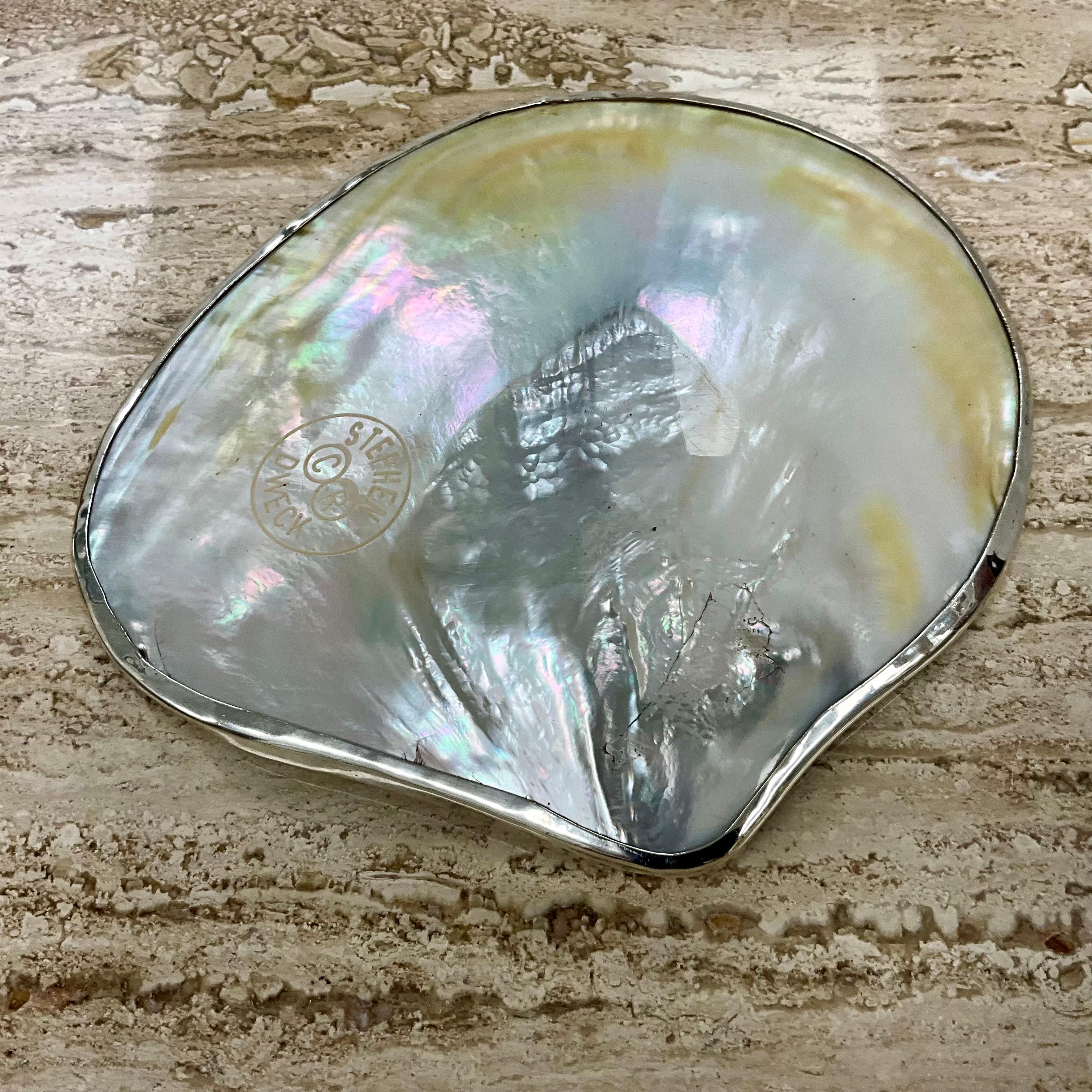Un piatto in argento e conchiglie di Stephen Dweck

Questo squisito piatto di Stephen Dweck presenta un design unico che combina l'argento sterling con una conchiglia naturale, creando un contrasto visivo sorprendente. La forma organica del piatto