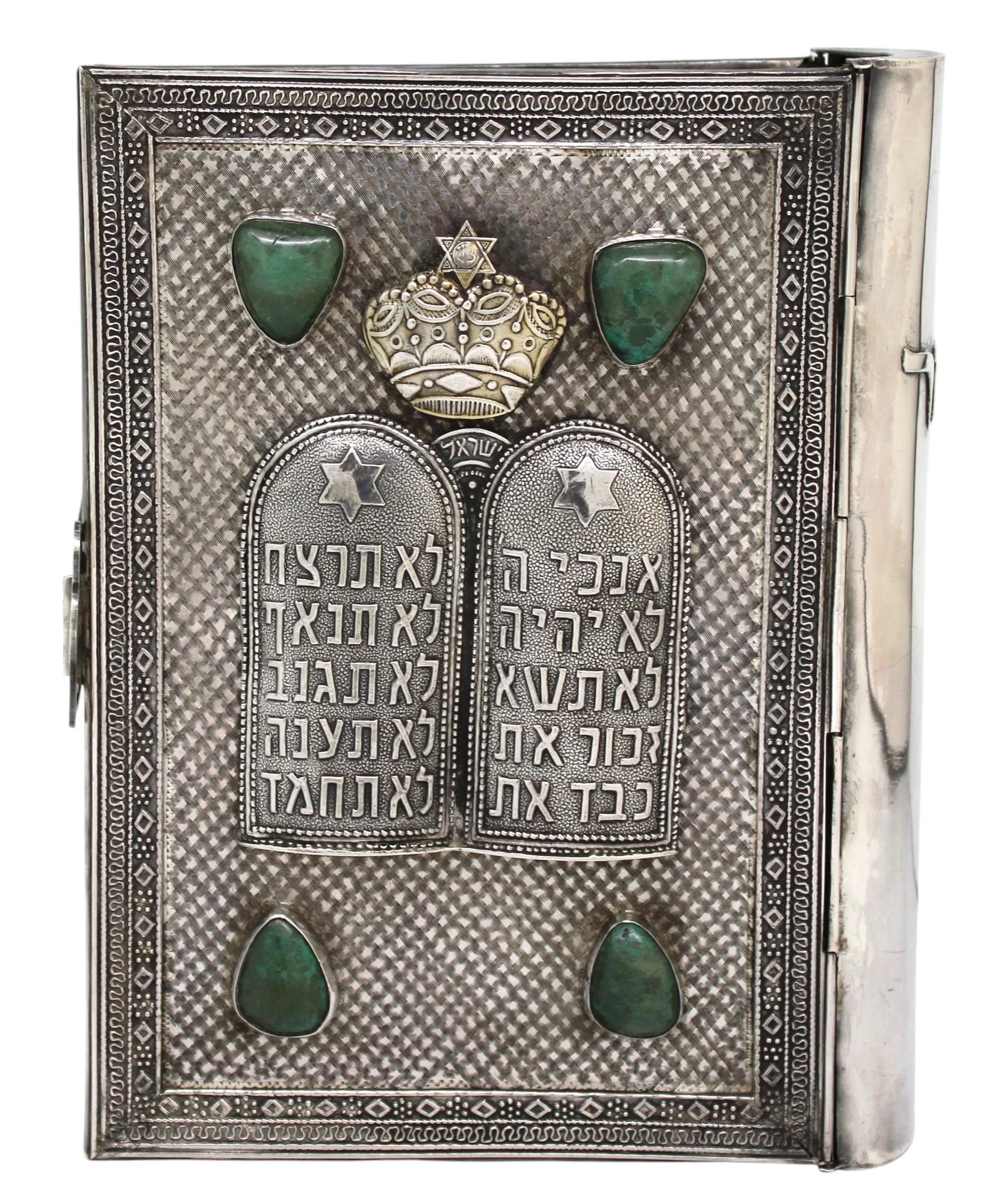 Questa squisita rilegatura del Siddur in argento sterling è un'opera magistrale di Judaica, realizzata con eccezionale maestria e devozione. La copertina anteriore è ornata da un'impressionante rappresentazione delle Luchot HaBrit (Tavole