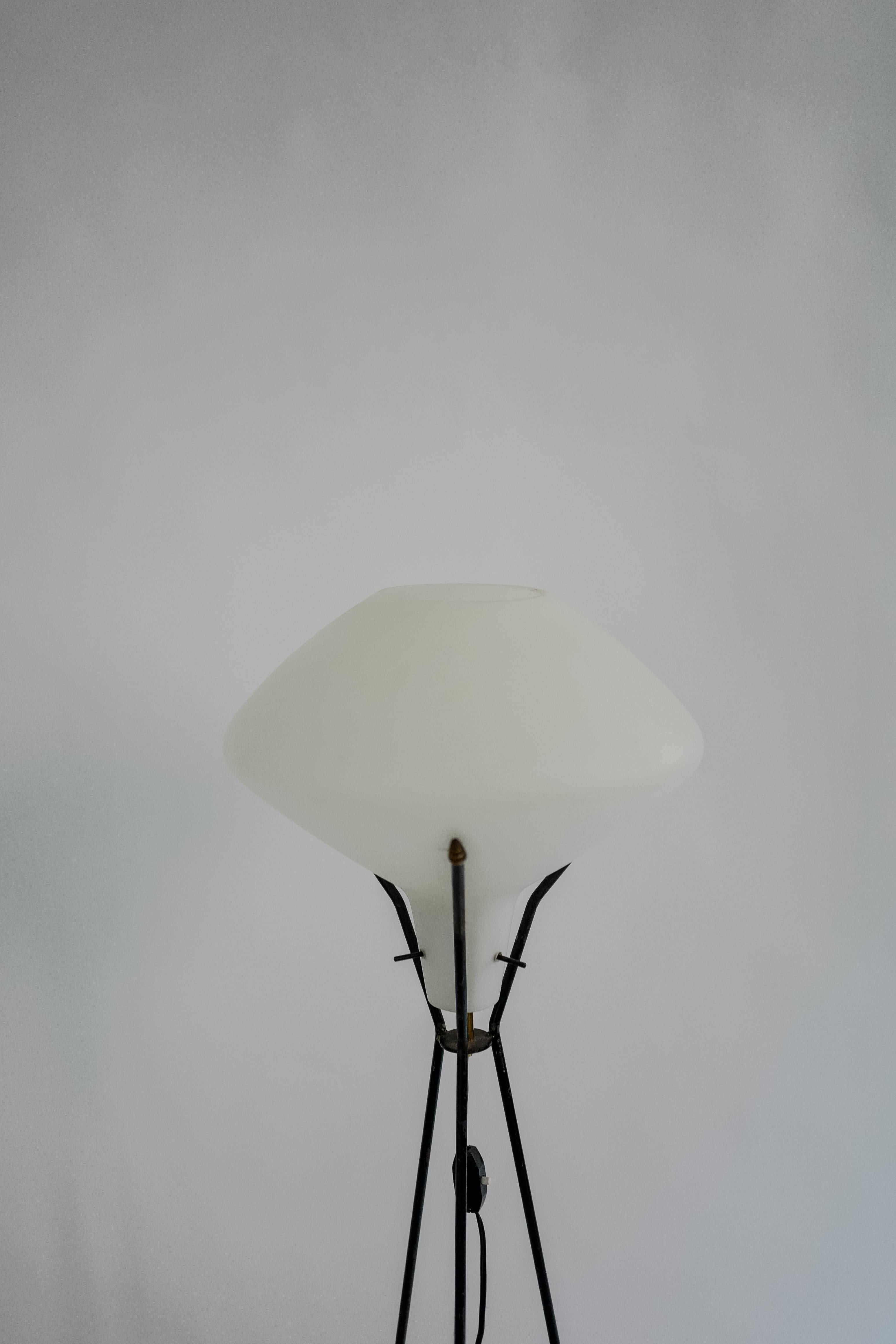 A Stilnovo style floor lamp with a metal tripod base and milk glass which is attached with metal pins. Wired for Europe circa 1960's.
