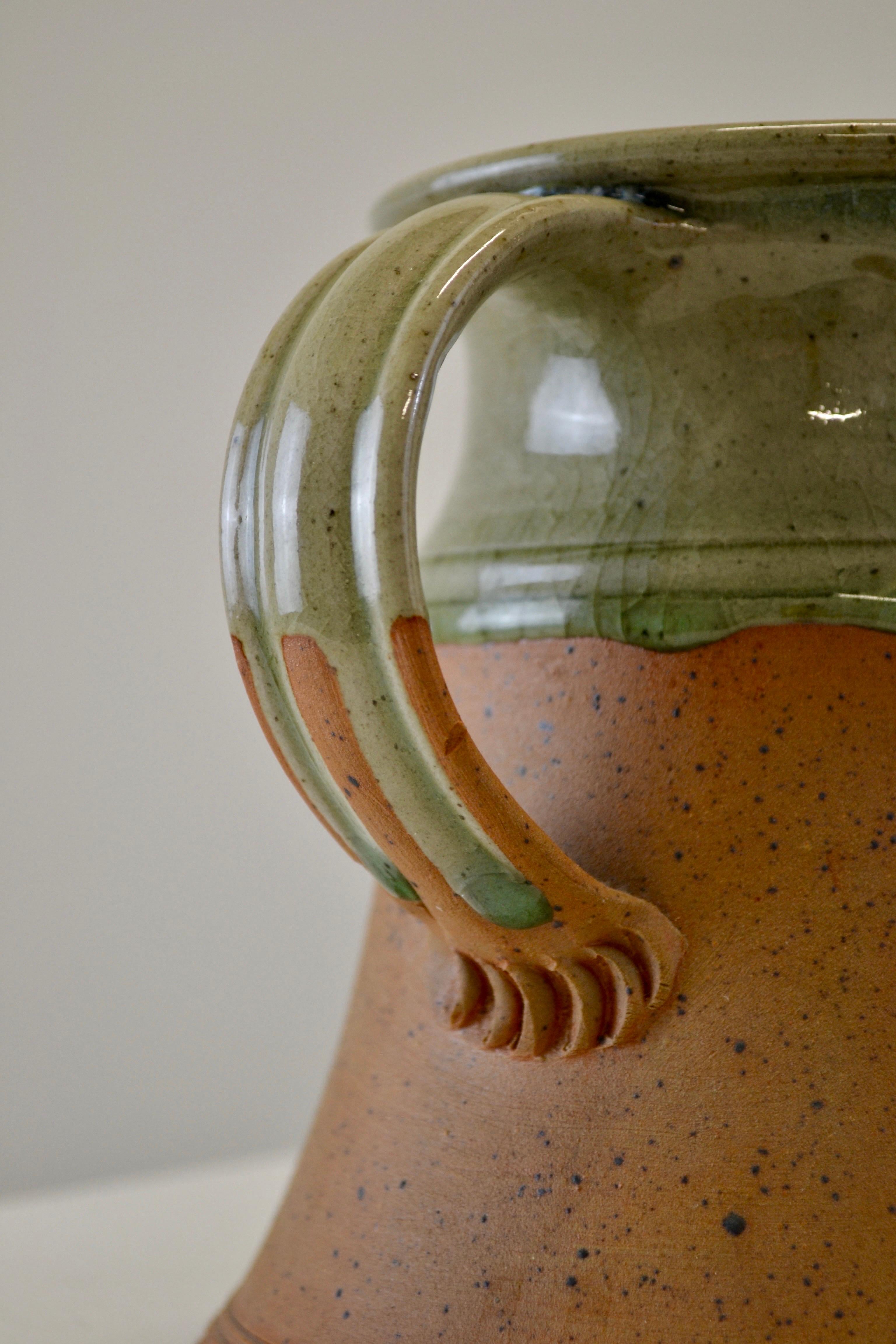 Brocca in gres attribuita a Pierre Digan, Francia, circa 1970. Questo elegante pezzo realizzato al tornio presenta un sorprendente contrasto tra la base in terracotta maculata non smaltata e la parte superiore rivestita con uno smalto crepla verde