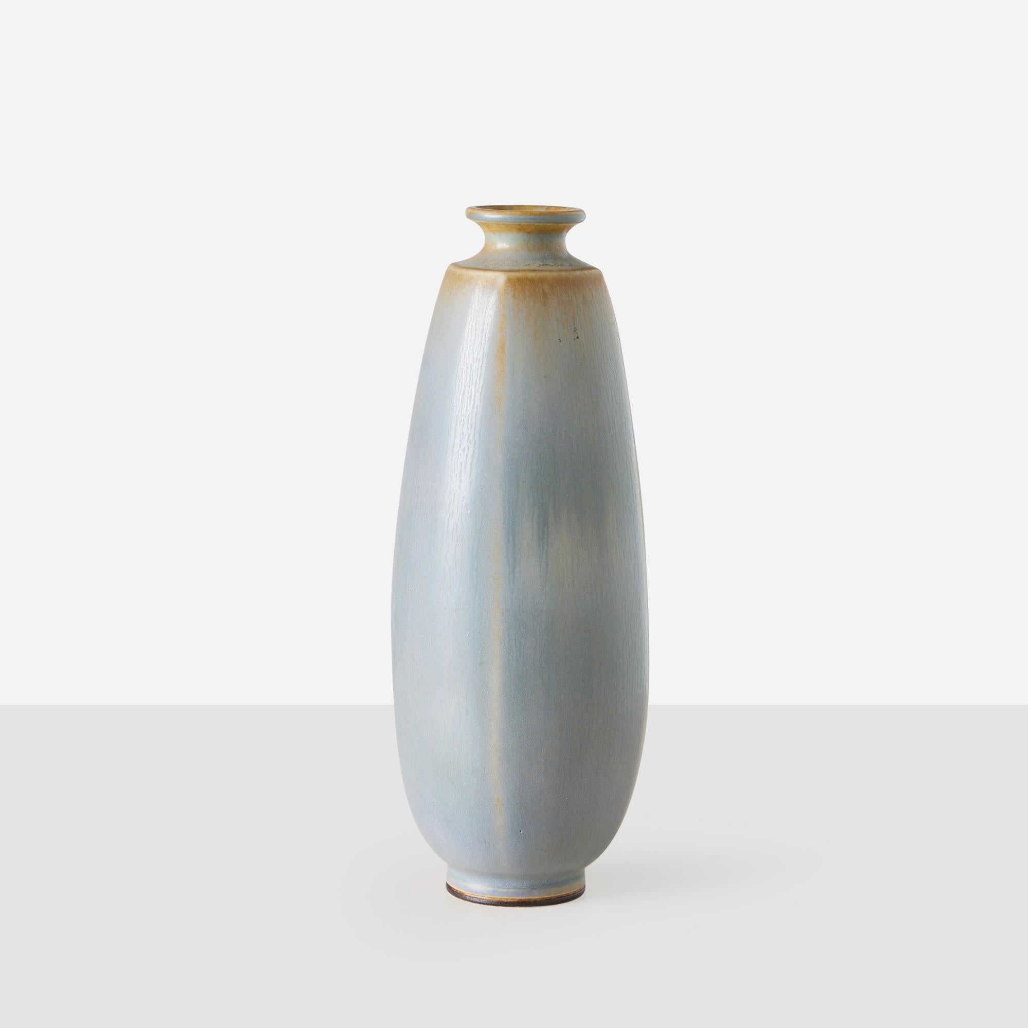 Questo vaso in gres di Berndt Friberg, lavorato a ruota, presenta un collo robusto e sottile e uno smalto liscio nelle tonalità del blu e del grigio chiaro. È un esempio della raffinata maestria artigianale e dell'eleganza delle forme di Friberg. Il