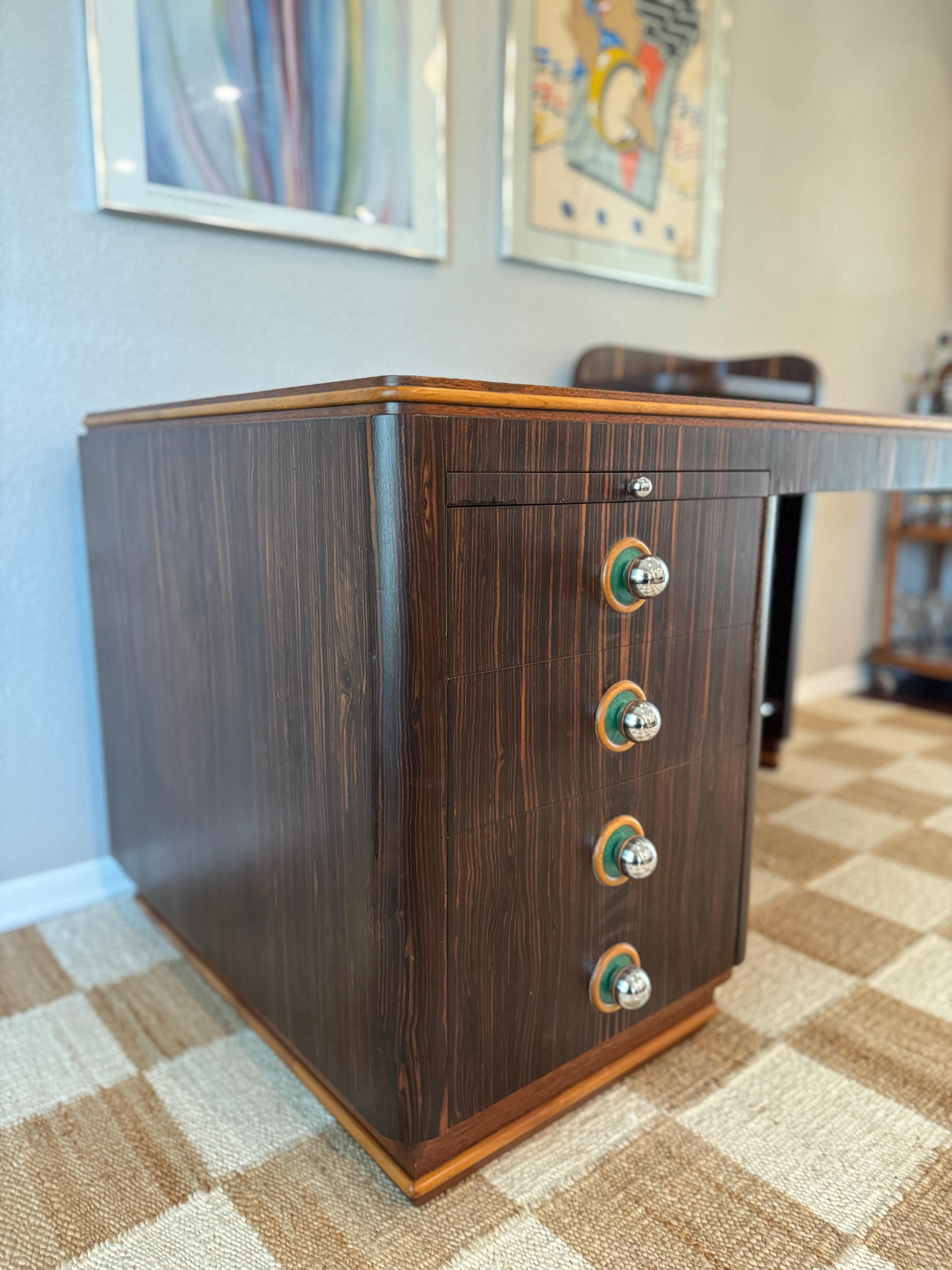 A stunning piece from the timeless Art Deco era, circa 1930s, showcasing the elegance and luxury of the period. Crafted in rich rosewood veneer with striking Streamline Moderne influences, its bold linear grain is framed by warm contrasting edges.