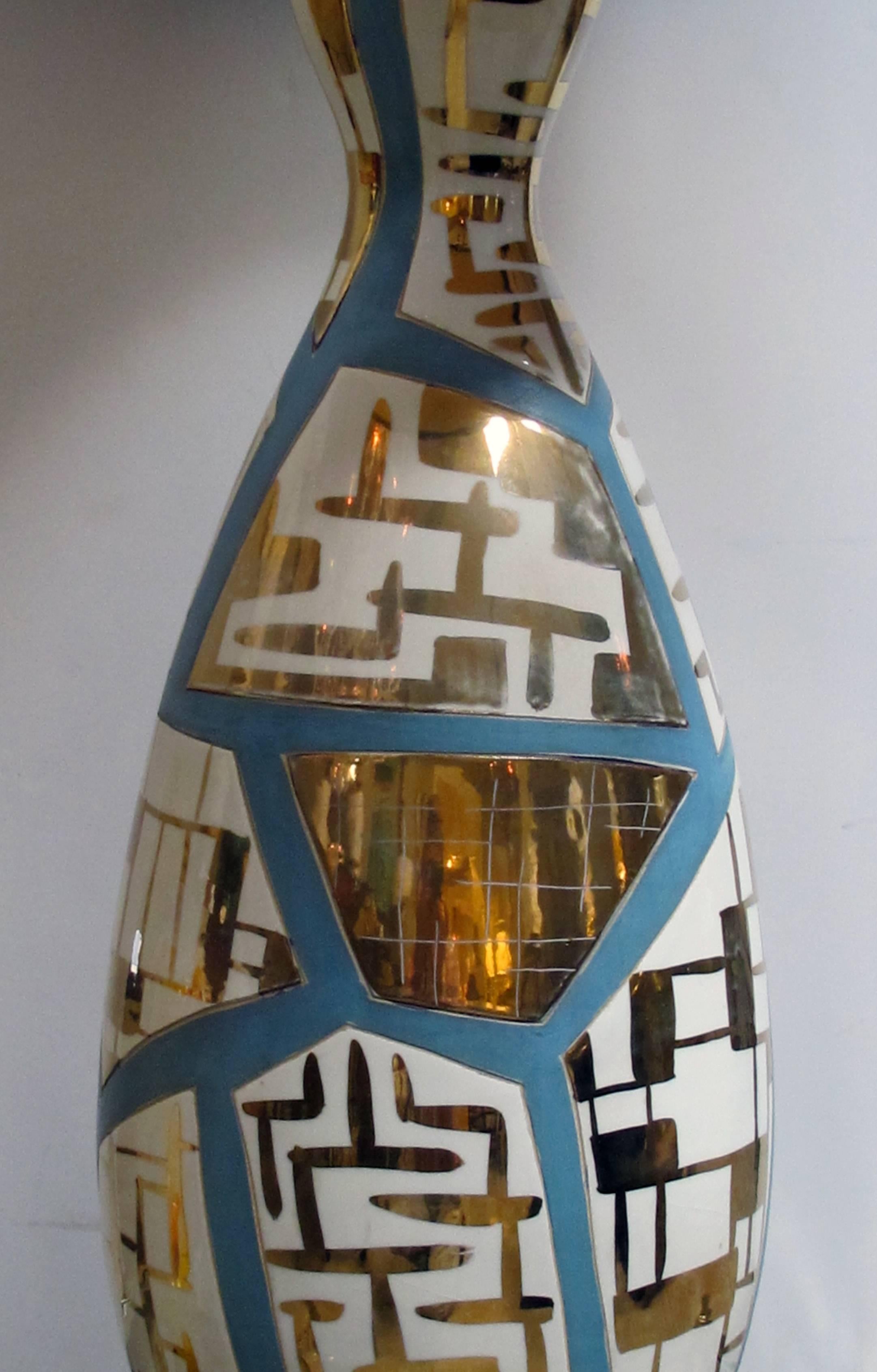 A striking and tall pair of Italian midcentury bottle-form lamps with gilt geometric decoration; each of bottle form adorned overall with geometric reserves with gilt decoration divided by pale blue painted stringing.