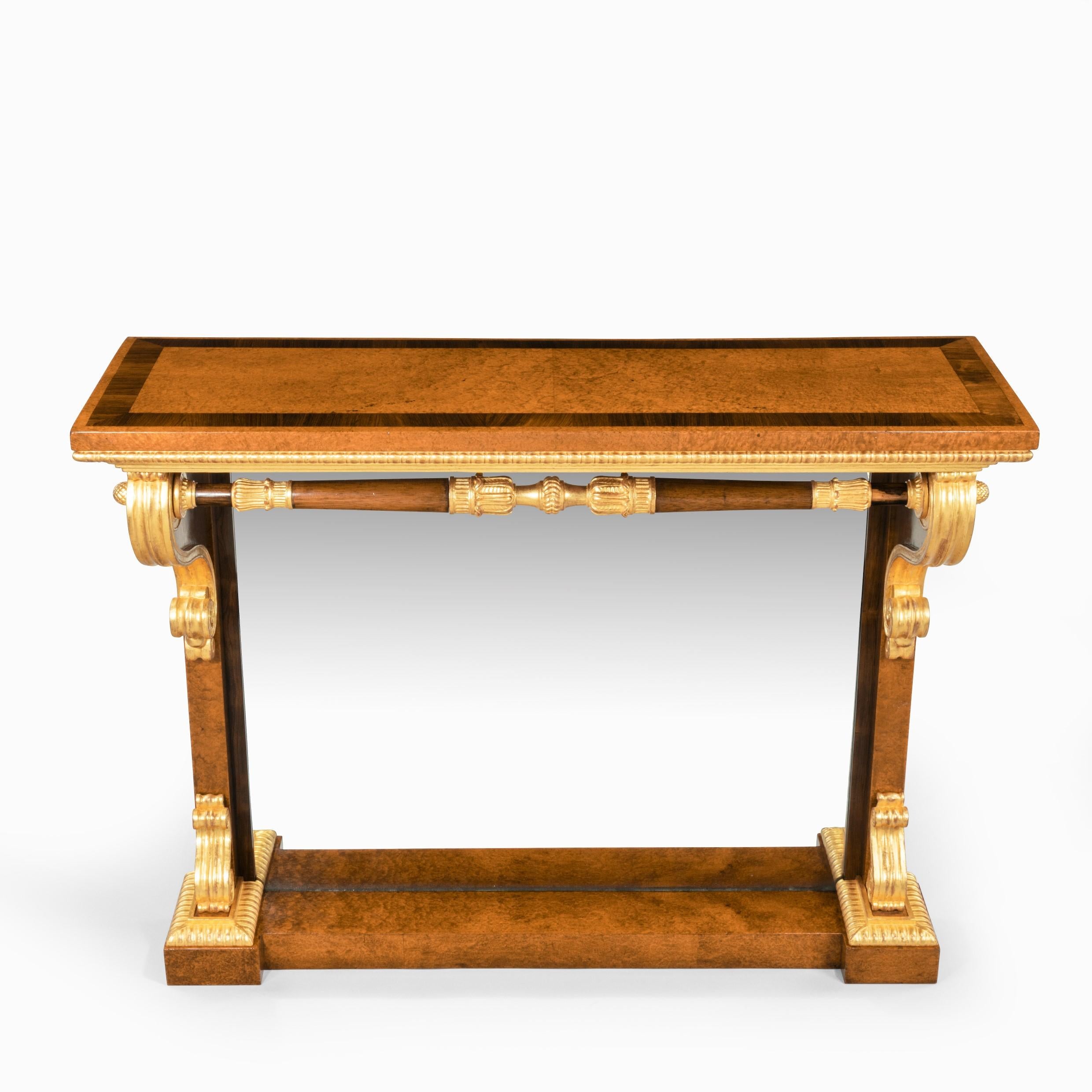 Magnifique table console en amboine, bois de rose et bois doré de style George IV, attribuée à Morel et Seddon, le plateau rectangulaire surmontant deux monopodes avec des corbeaux et des pieds en bois doré reliés par une civière tournée et