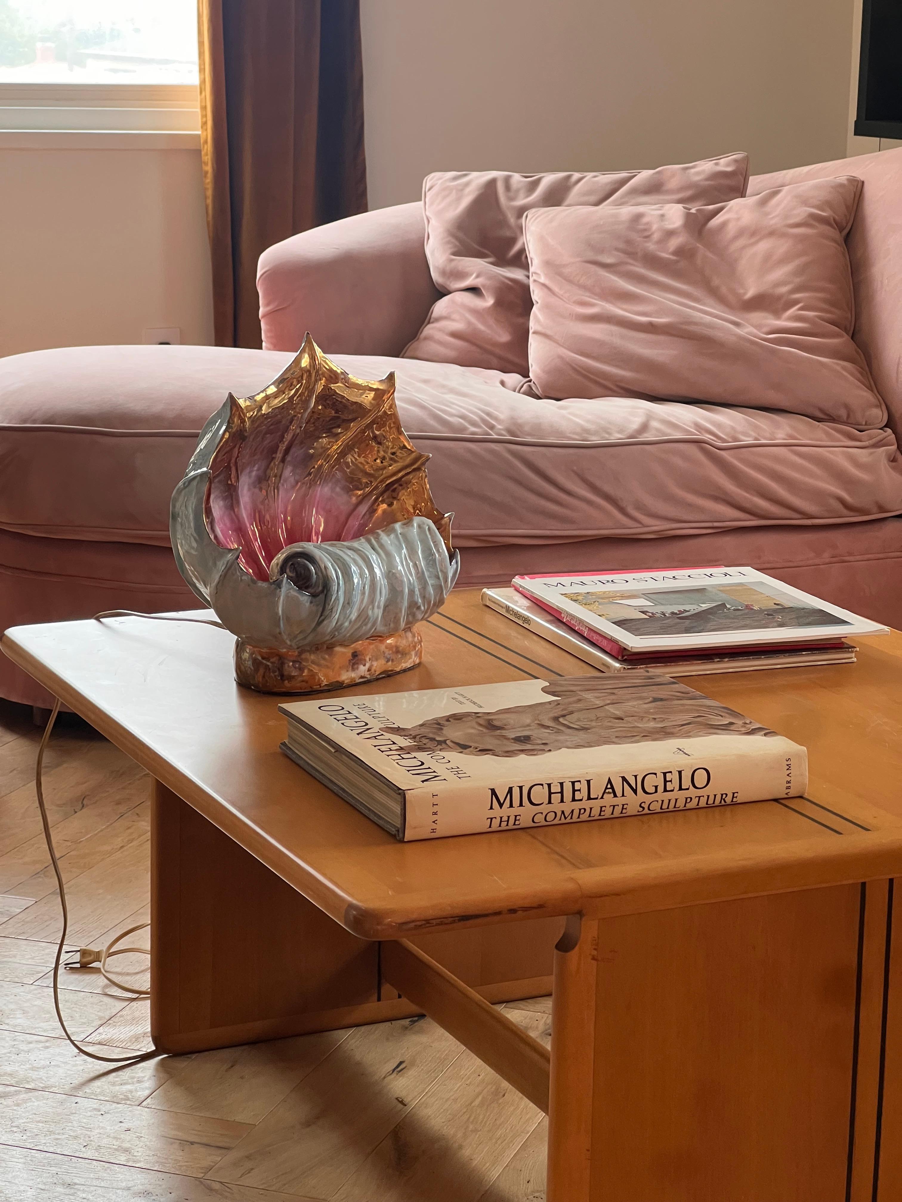 An absolutely outrageous hand-crafted ceramic conch shell lamp, late 1950s. This stunning statement piece glimmers like the shell of Aphrodite herself: warm ombré hues of pink and copper adorn the interior of the conch, while the outside is a pearly