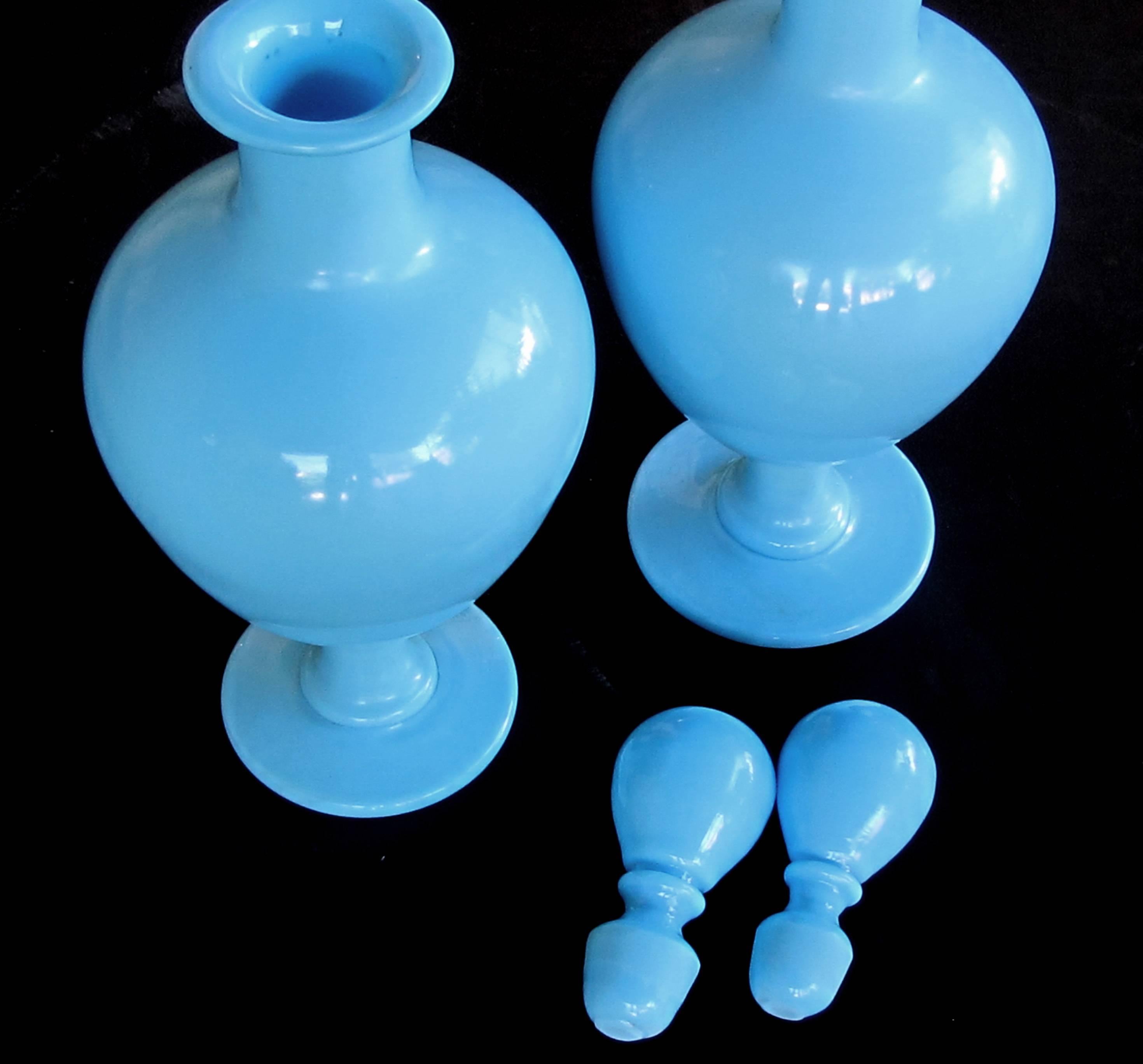 Each ovoid decanter of opaque blue glass fitted with an orb-shaped stopper; all resting on a flared base.