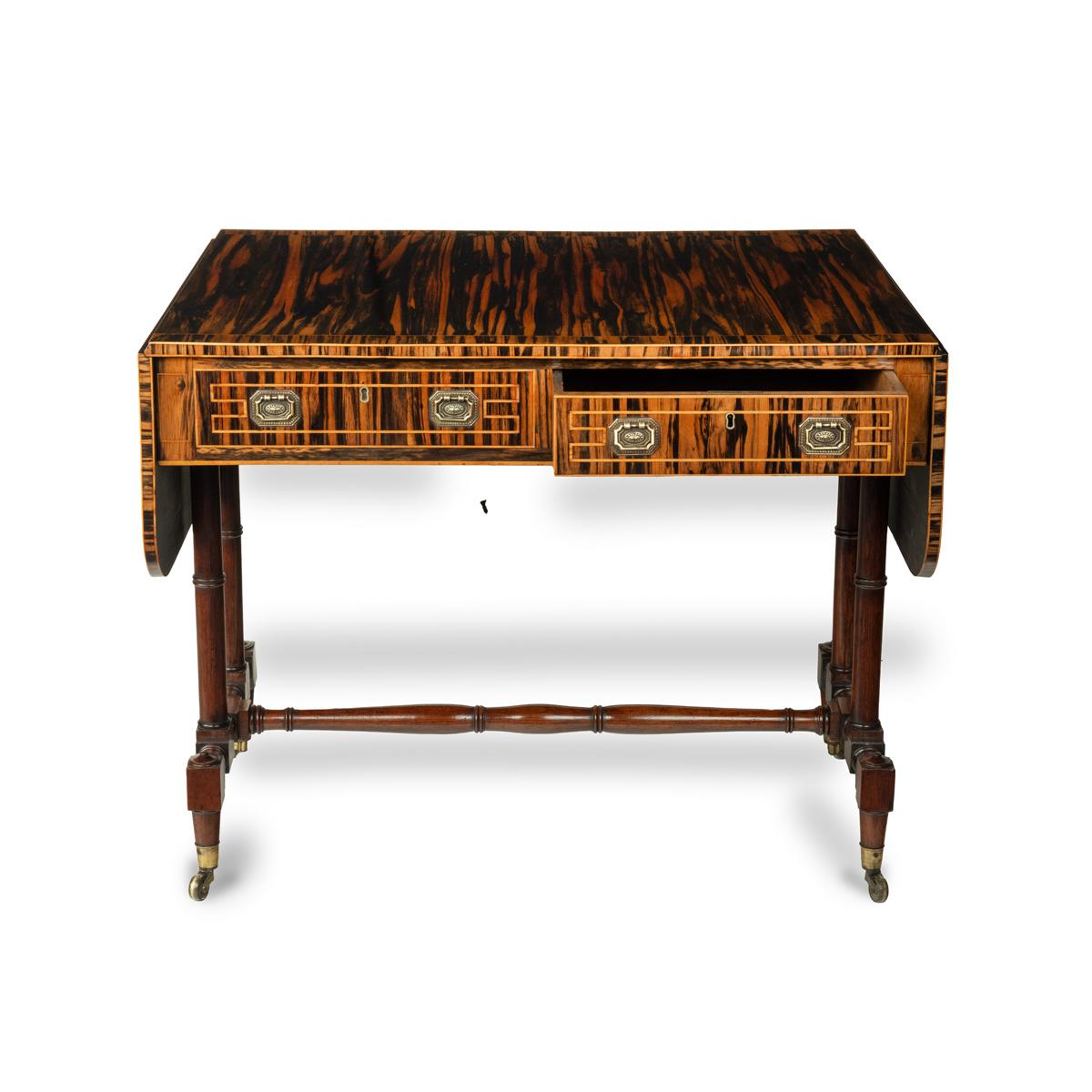 A striking Regency coromandel sofa table, of typical rectangular form with two rounded flaps, each side has one frieze drawer and one dummy drawer, with turned double column supports and stretcher, original castors, decorated throughout with book