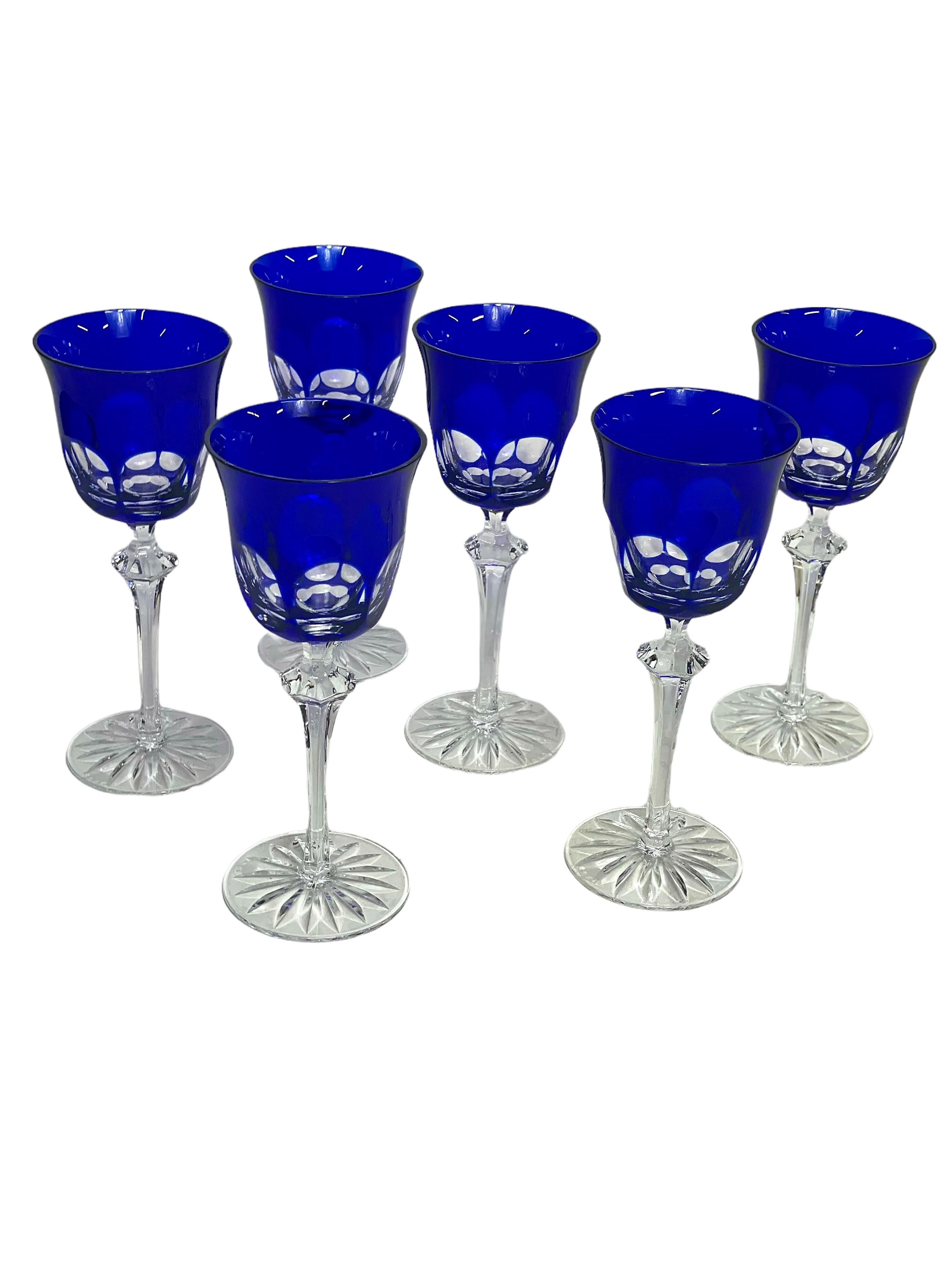 A striking set of six cobalt blue overlay cut-to-clear crystal Rhine wine glasses, with a cupped bowl, tall knopped stem and flat, round, star-cut pedestal. The crystal blue overlay is cut around the base of each bowl to reveal a set of