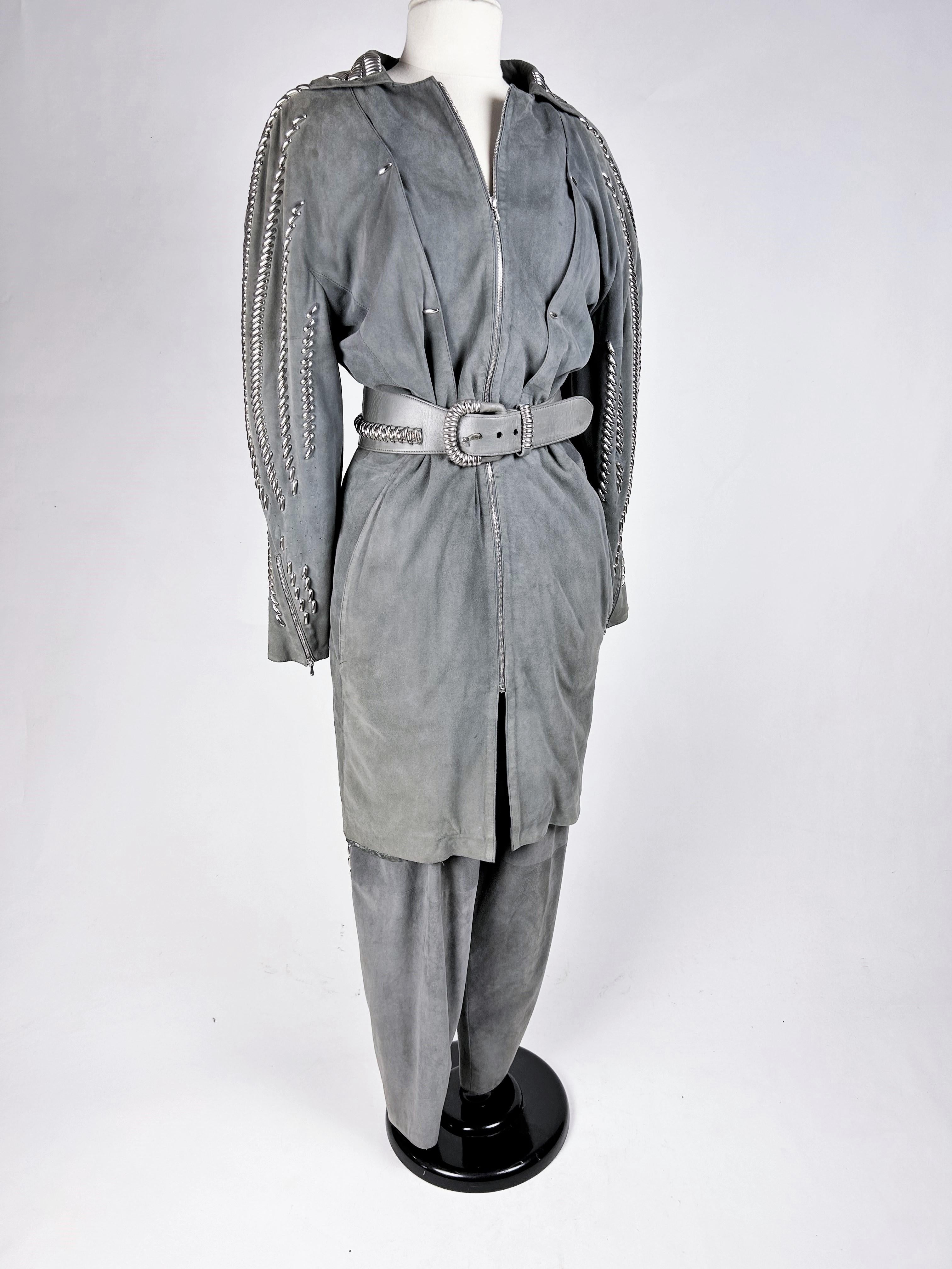 Circa 1985

France

Grey suede jacket and trouser suit by Claude Montana dating from the 1980s. Long zip-front jacket with architectural long sleeves, emphasised by waves studded with silver metal and echoed on the trousers and matching belt.