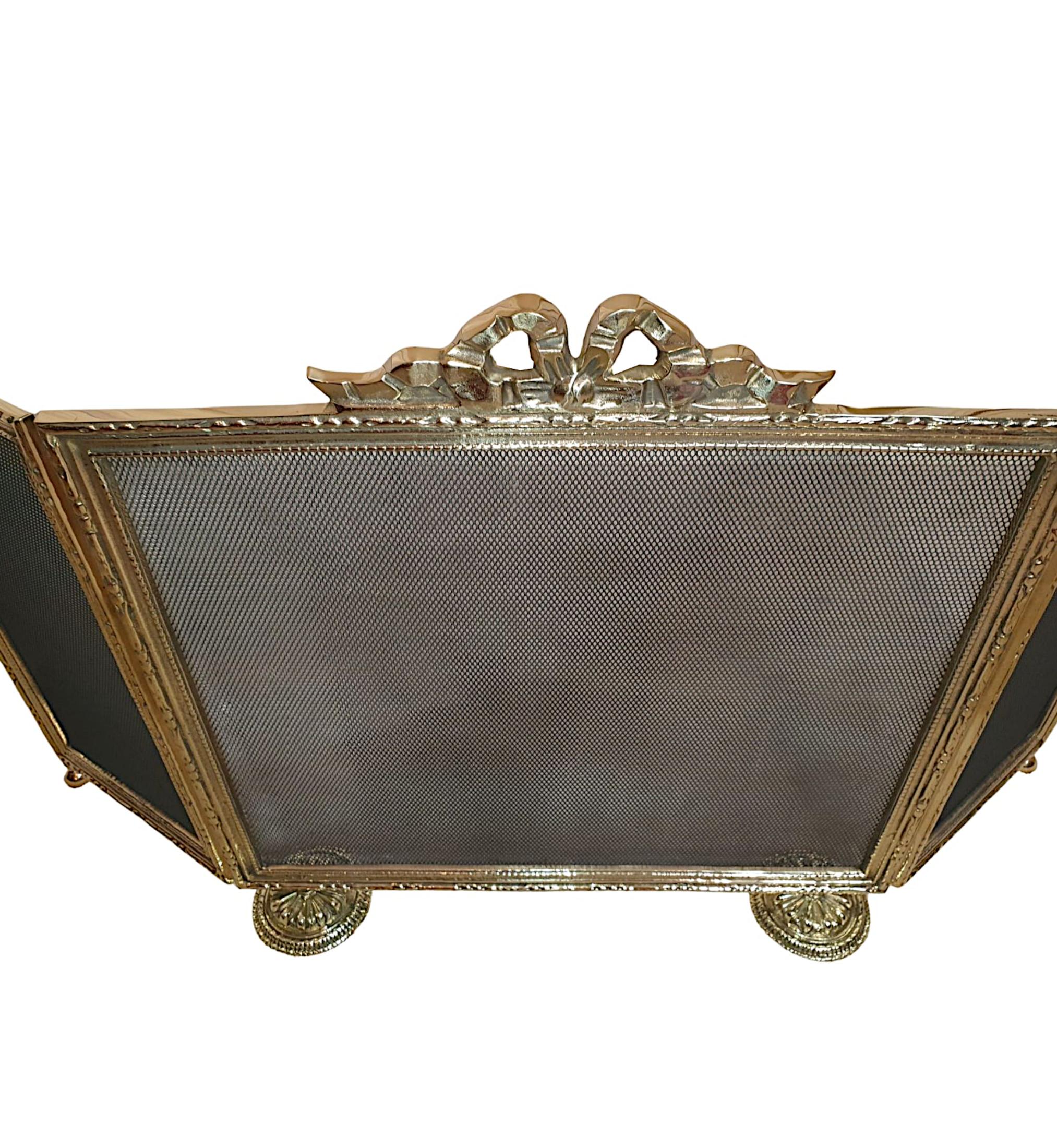 A stunning 19th century French free standing three panel brass fire screen. The protective mesh wire is set within a fine quality frame surmounted with elegant carrying handle of ribbon bow mo-tif. The frame is intricately embossed with decorative