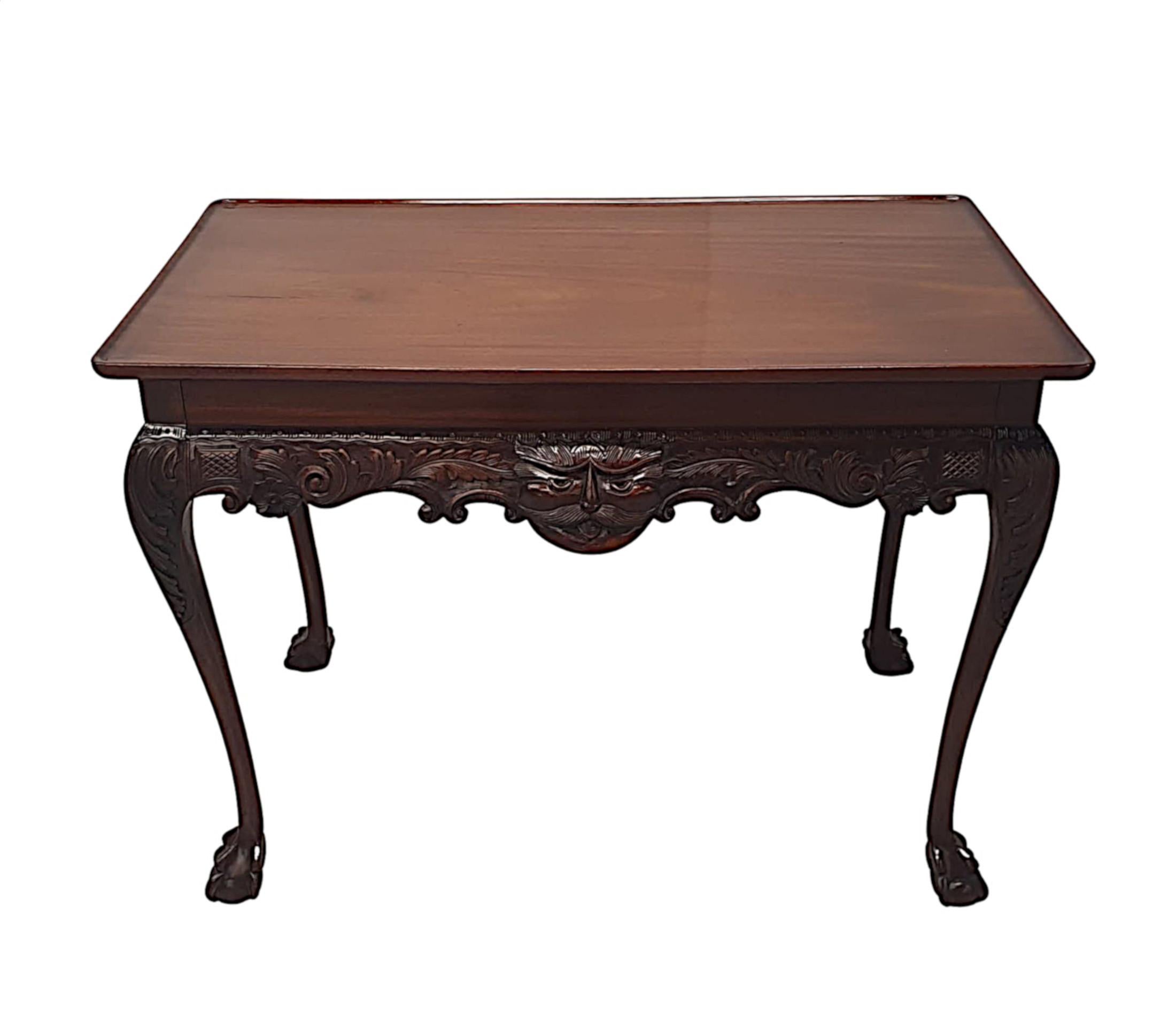 A stunning 19th century Irish solid mahogany console, side or hall table, beautifully hand carved with rich patination and grain. The moulded rim top raised over shaped apron with centred mask, intricately carved in high relief flanked with trailing