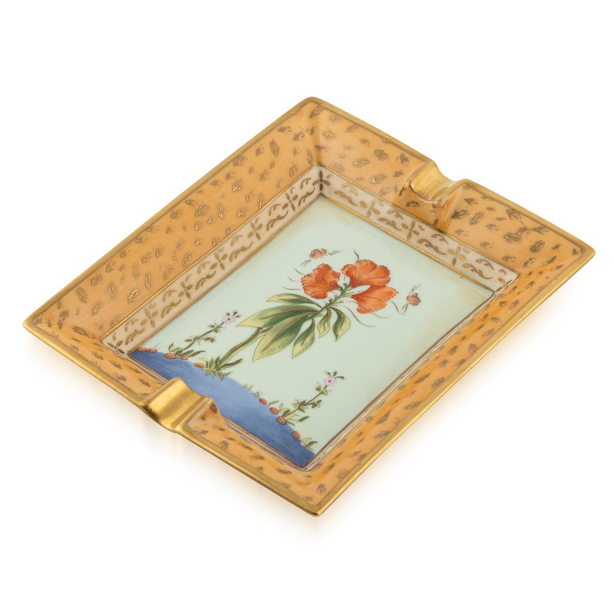 Este elegante cenicero de cerámica de Hermès, fabricado en Francia durante el siglo XX, ejemplifica la dedicación de la Casa al arte y el refinamiento. La pieza presenta un elegante motivo orgánico: una exquisita representación de una planta en flor