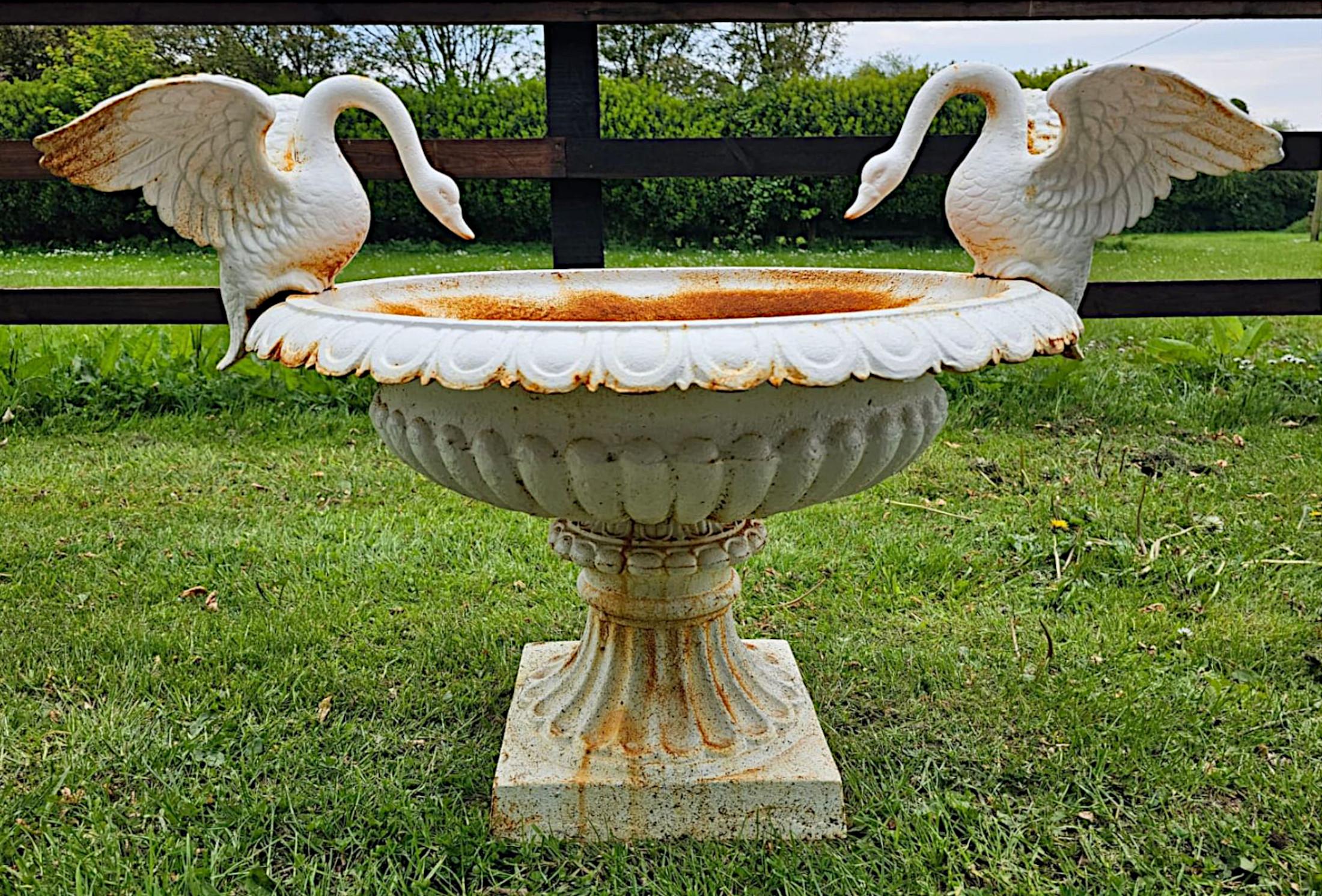 A stunning pair of 20th Century heavy cast iron urns of large proportions, finely crafted and of exceptional quality.  Surmounted with a fabulously detailed pair of swans, raised over a shaped, everted rim of oval form and beautifully adorned