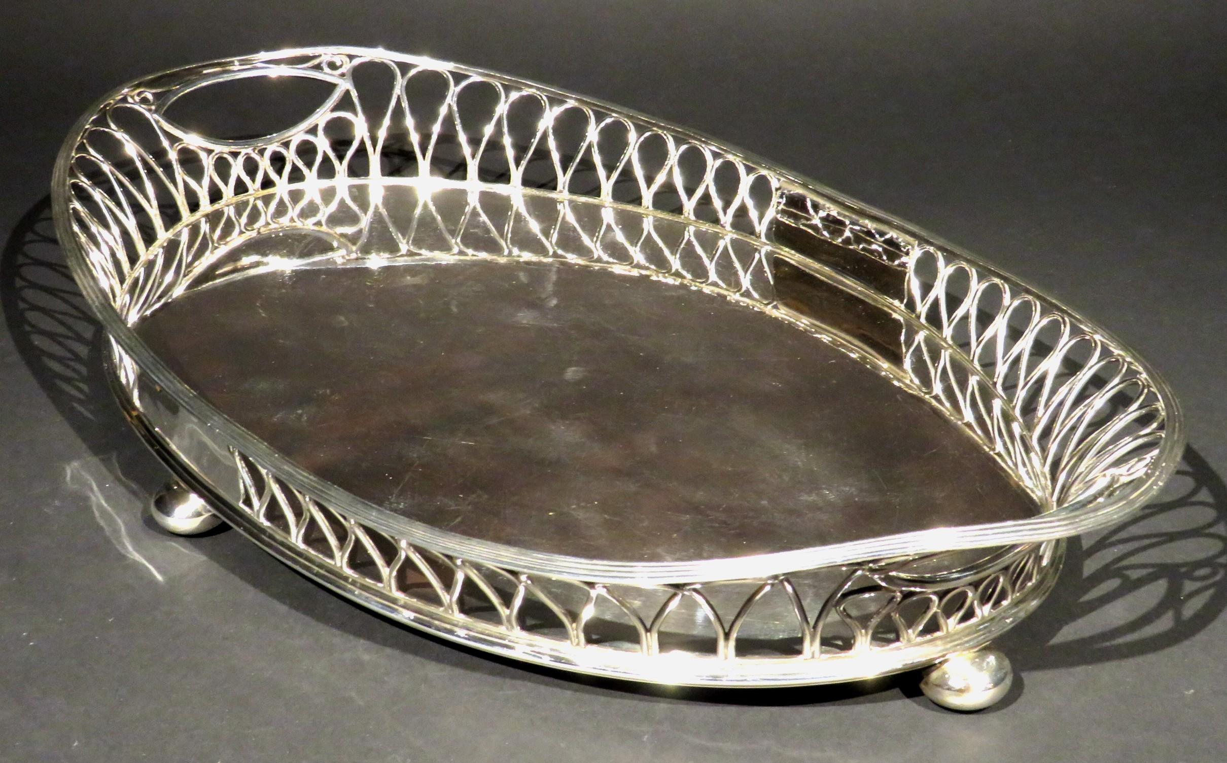 A very good & highly stylized Art Nouveau period silver plated gallery tray of navette form, showing an oval base surrounded by a striking open-work gallery of interlaced loop-shaped elements, rising up at both ends to open handles and raised