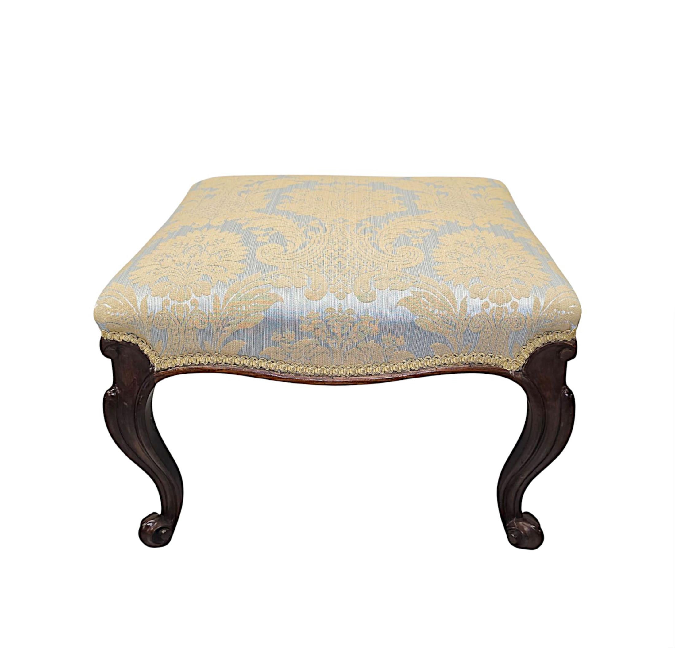 A stunning 19th Century finely hand carved, well figured mahogany foot stool, fully restored and of exceptional quality with rich patination and beautiful grain.  The cushioned seat of rectangular form is upholstered in a gorgeous cream fabric with