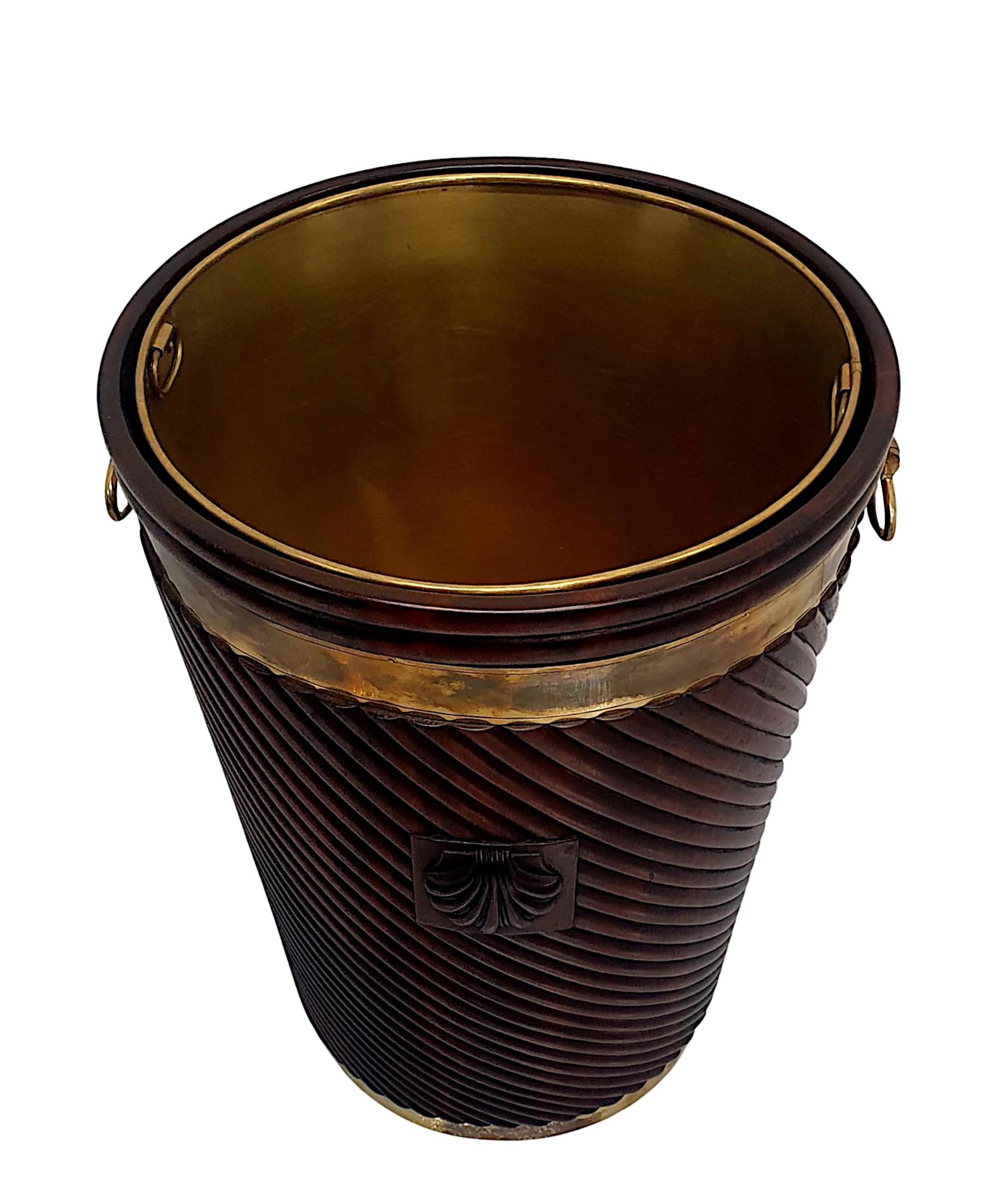 A stunning Irish design mahogany brass bound peat bucket of fabulous quality, large proportions and finely hand carved with rich patination and grain.  The moulded and reeded, brass bound body incorporates a gorgeous spiral twist pattern detail and